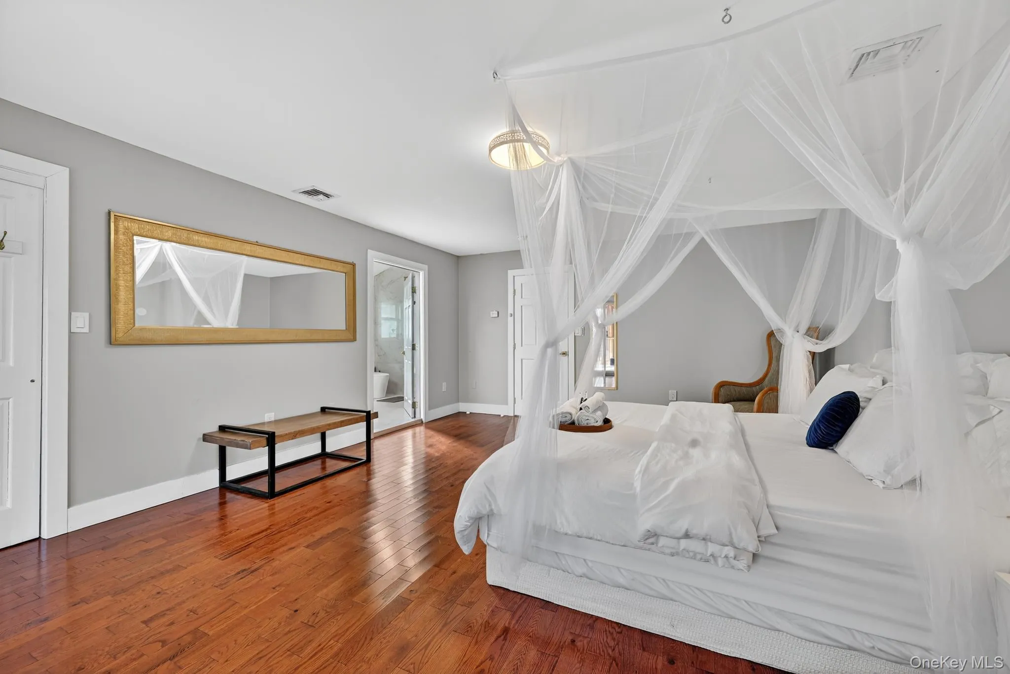 Primary Bedroom with hardwood floors leading to En Suite Bathroom Primary Bedroom with hardwood floors leading to En Suite Bathroom