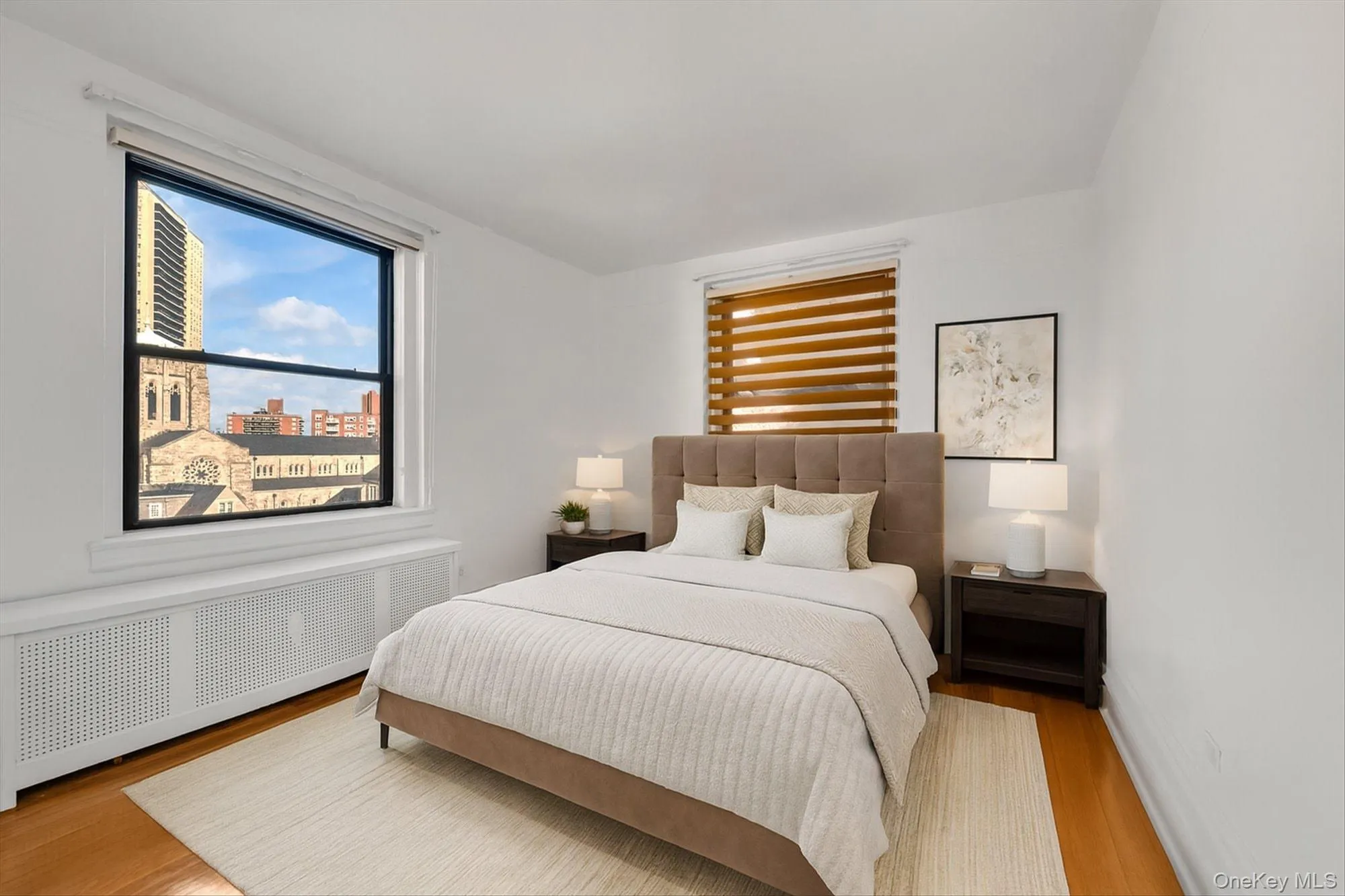 Bedroom featuring wood finished floors, radiator, and a city view Bedroom featuring wood finished floors, radiator, and a city view