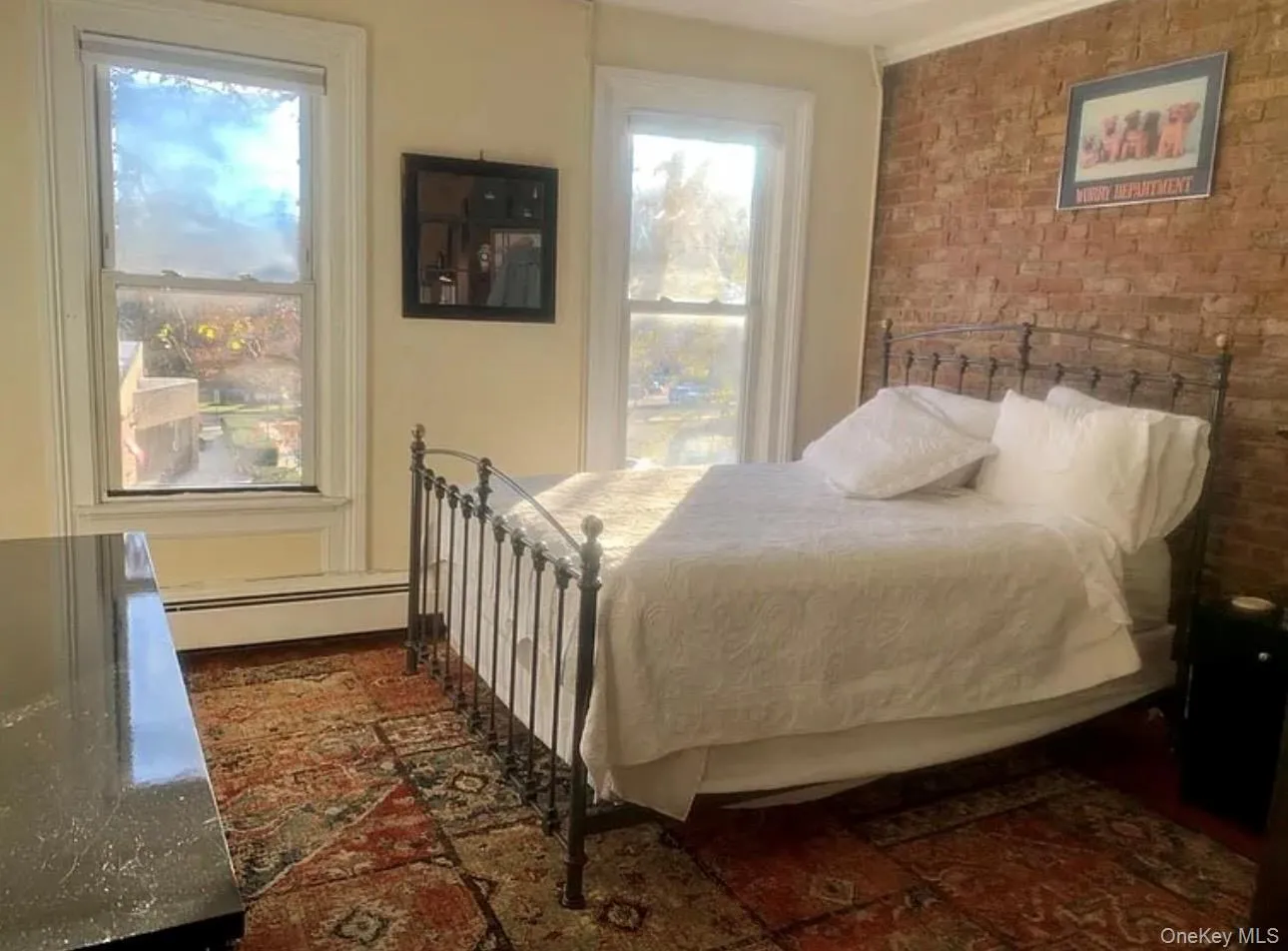 Bedroom featuring brick wall and a baseboard radiator Bedroom featuring brick wall and a baseboard radiator