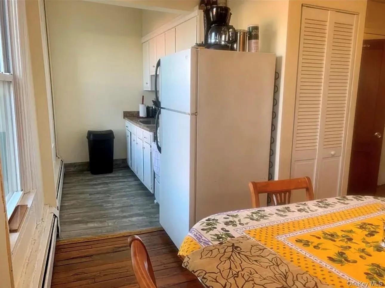 Kitchen featuring white cabinets, freestanding refrigerator, dark wood-style flooring, and a baseboard radiator Kitchen featuring white cabinets, freestanding refrigerator, dark wood-style flooring, and a baseboard radiator