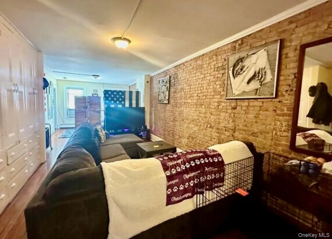 Living area featuring brick wall and ornamental molding Living area featuring brick wall and ornamental molding