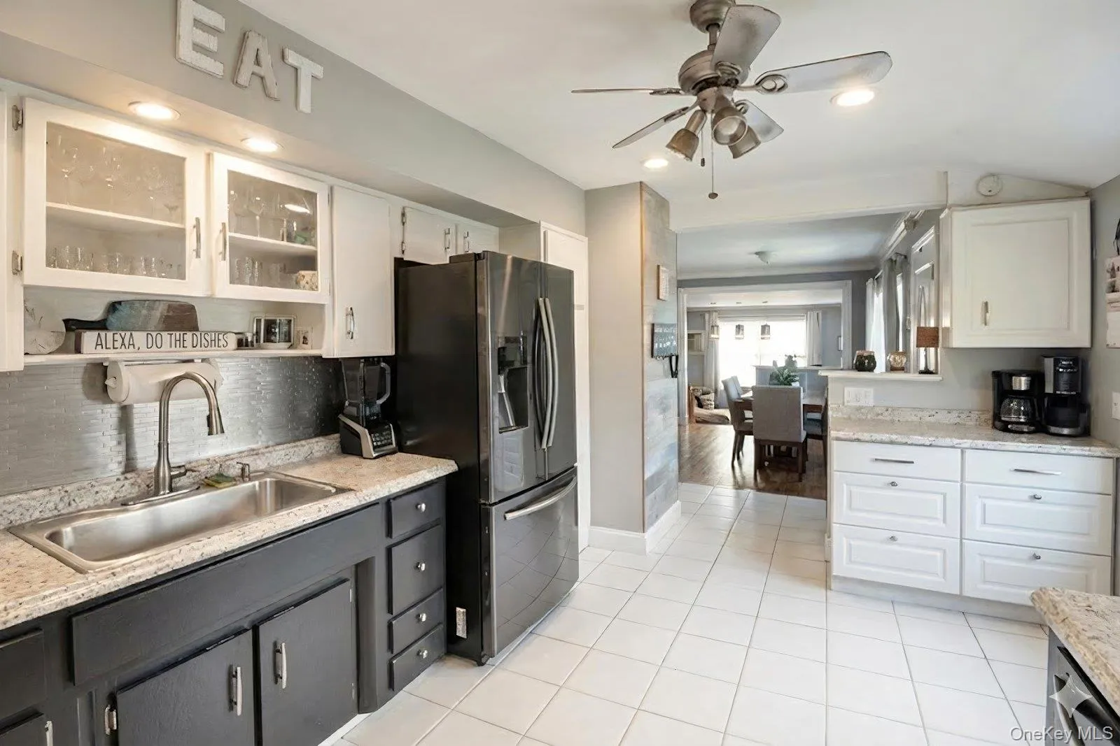 Kitchen featuring white cabinetry, stainless steel fridge with ice dispenser, glass insert cabinets, a ceiling fan, and light tile patterned flooring Kitchen featuring white cabinetry, stainless steel fridge with ice dispenser, glass insert cabinets, a ceiling fan, and light tile patterned flooring