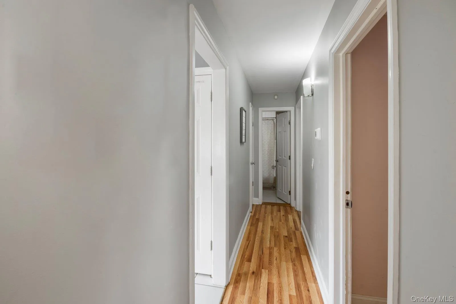 Corridor featuring baseboards and light wood finished floors Corridor featuring baseboards and light wood finished floors