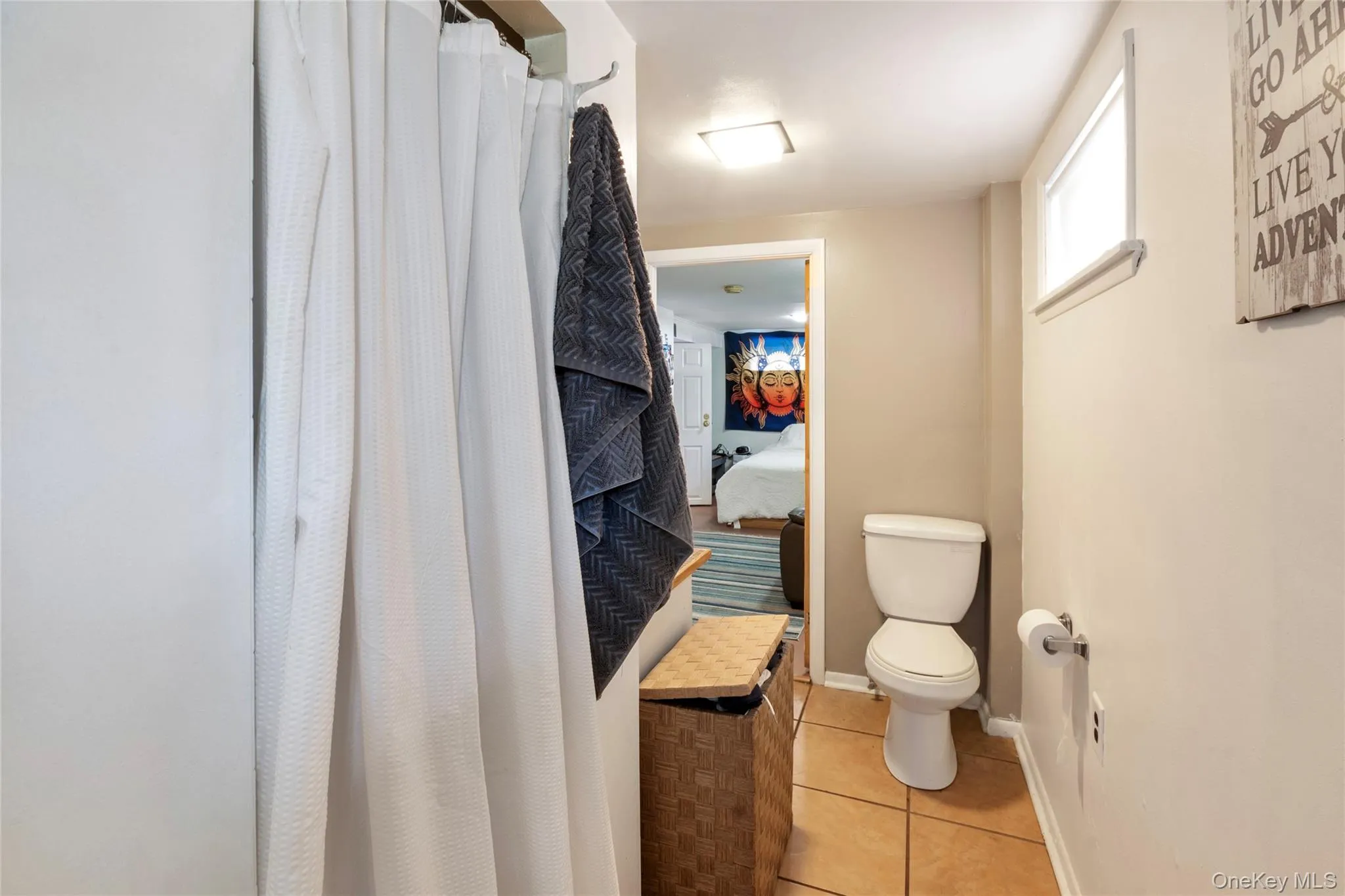 Ensuite bathroom featuring a shower with curtain and light tile patterned flooring Ensuite bathroom featuring a shower with curtain and light tile patterned flooring