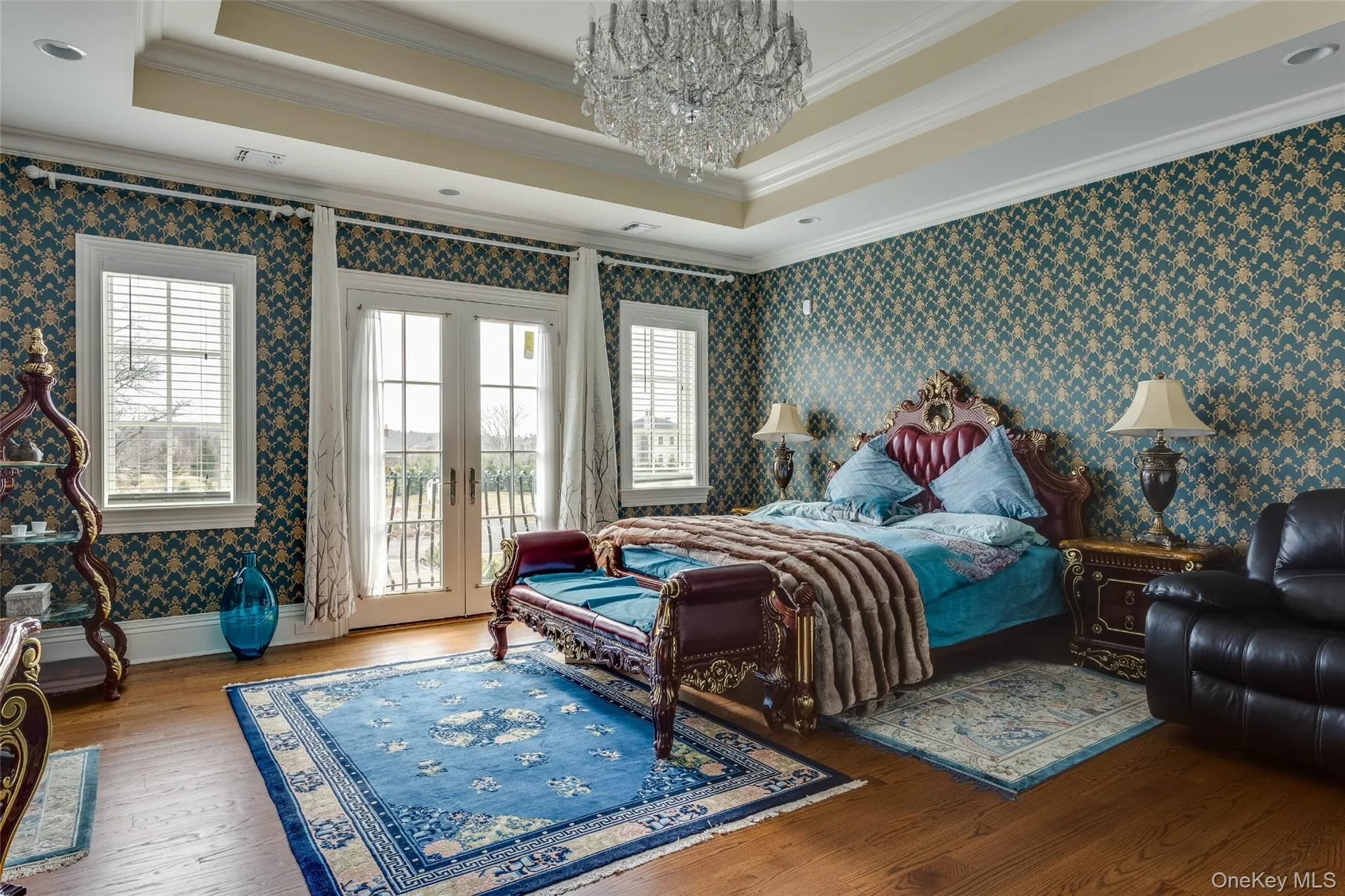 Bedroom with wallpapered walls, a tray ceiling, crown molding, a chandelier, and access to exterior Bedroom with wallpapered walls, a tray ceiling, crown molding, a chandelier, and access to exterior