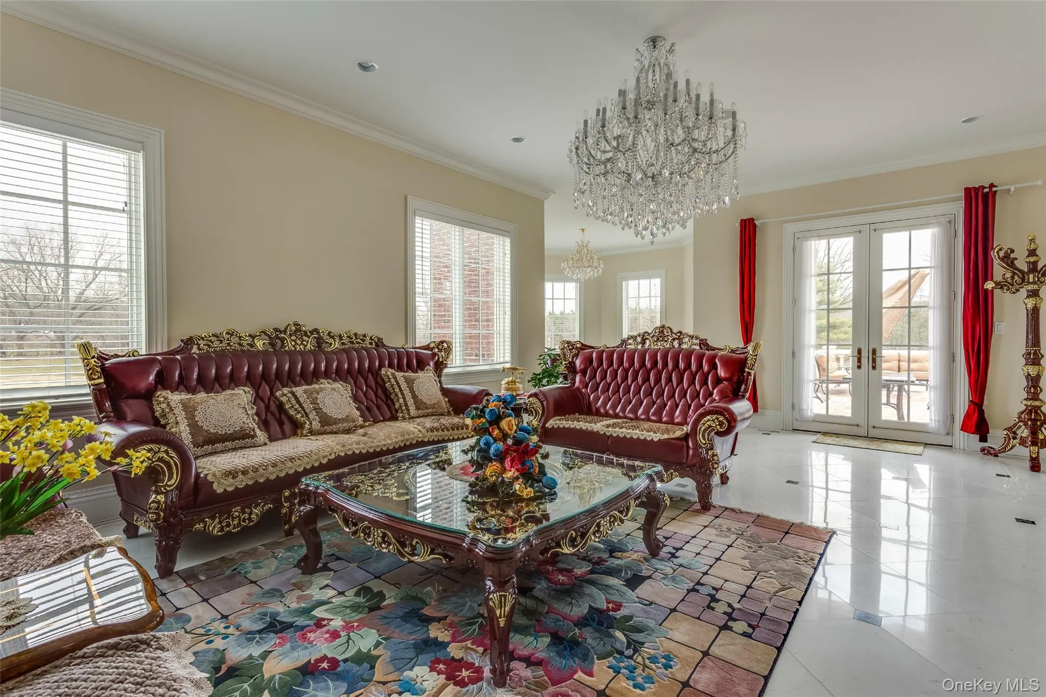 Living room featuring ornamental molding, healthy amount of natural light, a chandelier, tile patterned flooring, and french doors Living room featuring ornamental molding, healthy amount of natural light, a chandelier, tile patterned flooring, and french doors