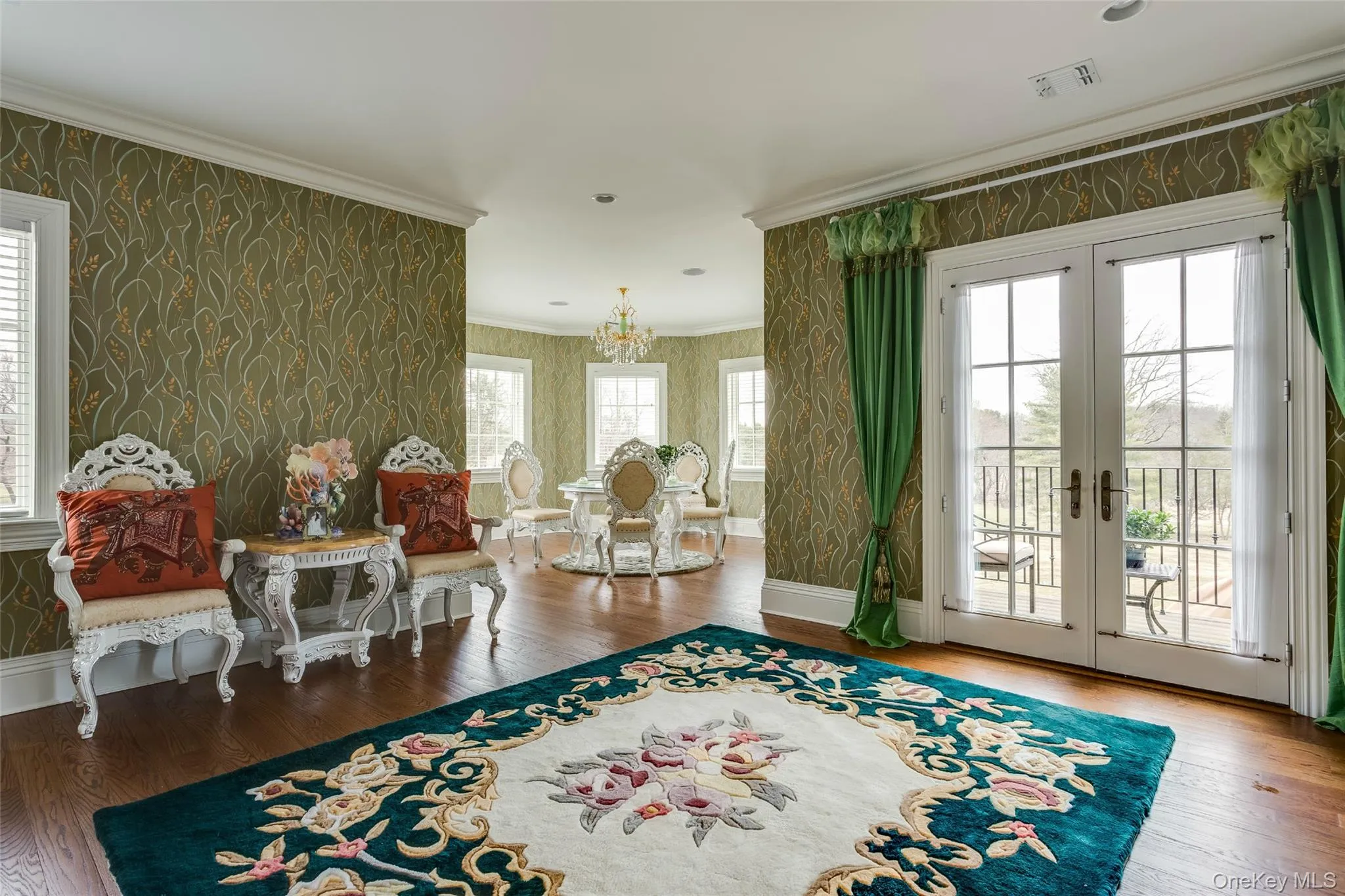 Living area with wallpapered walls, french doors, wood-type flooring, ornamental molding, and a chandelier Living area with wallpapered walls, french doors, wood-type flooring, ornamental molding, and a chandelier