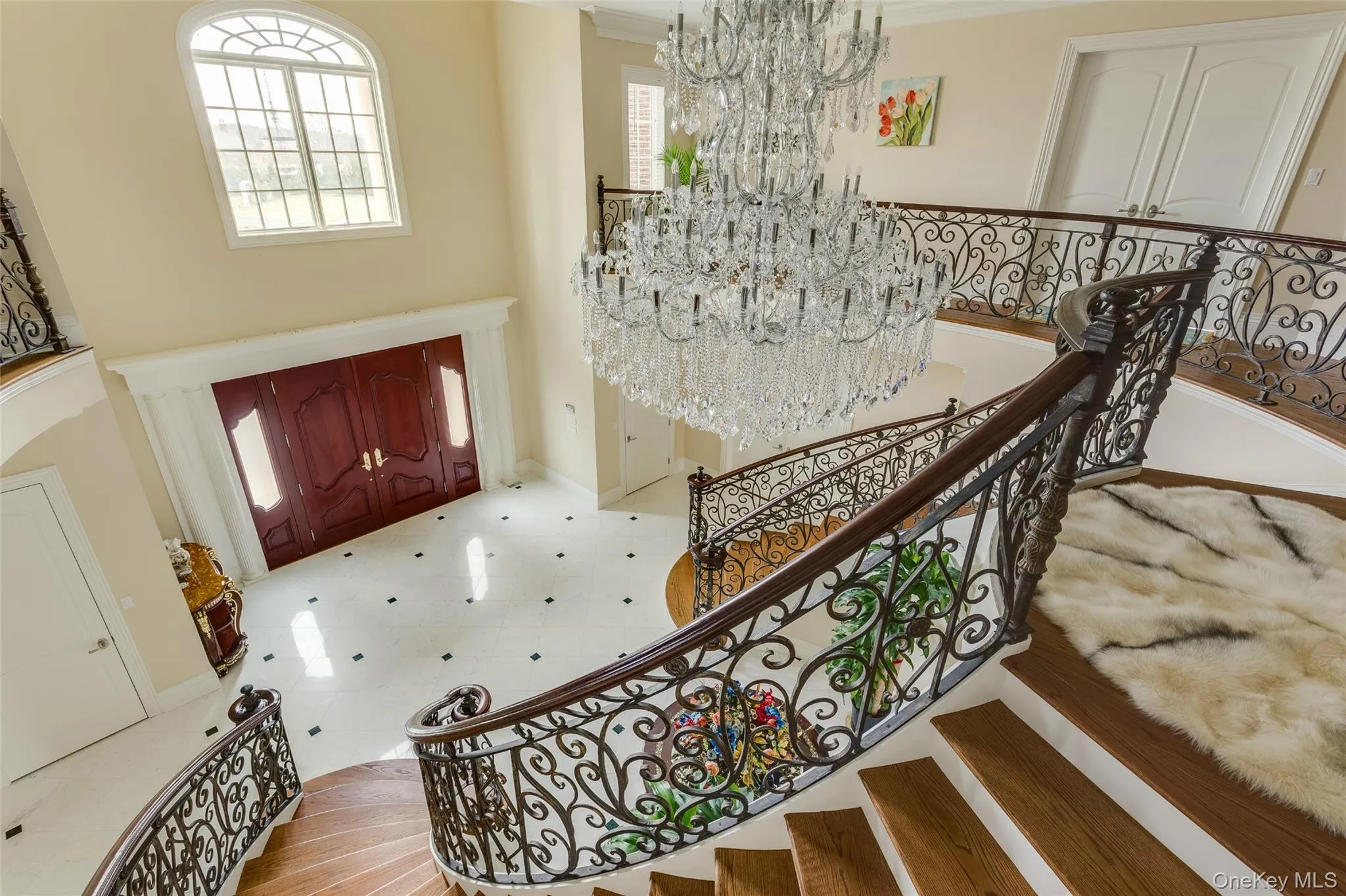 Entrance foyer with a chandelier, a towering ceiling, ornamental molding, and light floors Entrance foyer with a chandelier, a towering ceiling, ornamental molding, and light floors