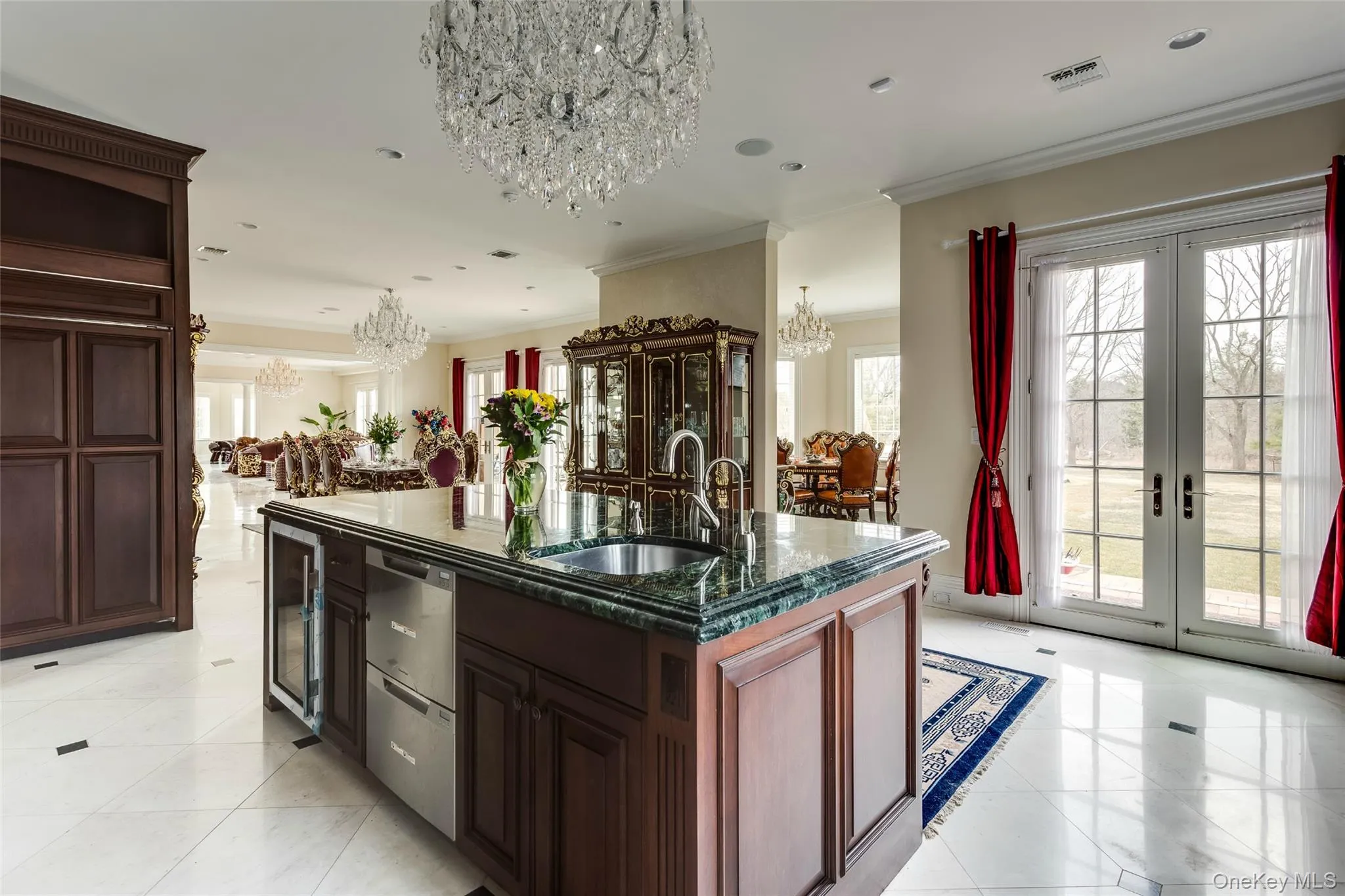Kitchen with dark brown cabinetry, a chandelier, a center island with sink, french doors, and ornamental molding Kitchen with dark brown cabinetry, a chandelier, a center island with sink, french doors, and ornamental molding