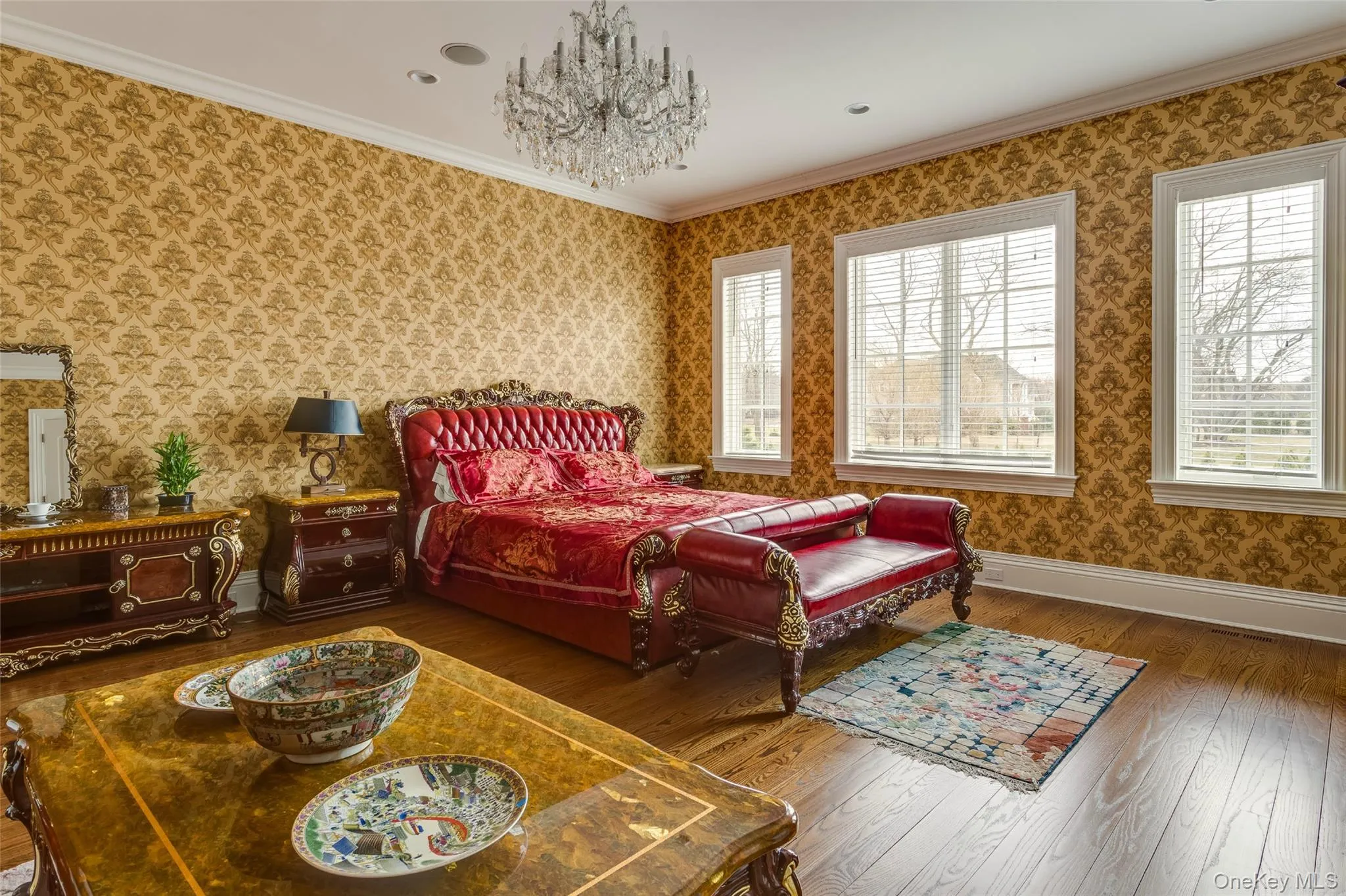 Bedroom featuring ornamental molding, wallpapered walls, a chandelier, and hardwood / wood-style floors Bedroom featuring ornamental molding, wallpapered walls, a chandelier, and hardwood / wood-style floors