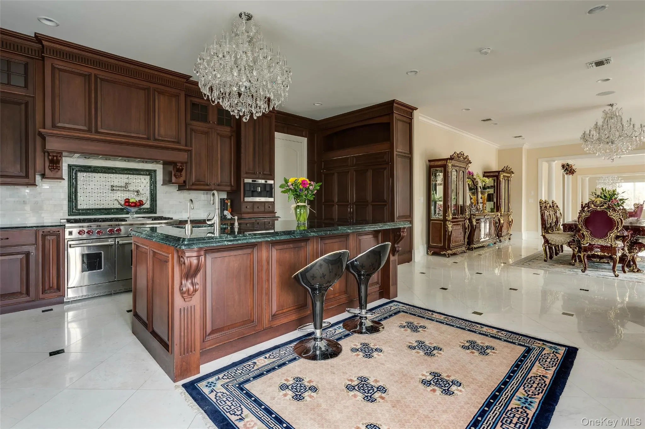 Kitchen featuring a chandelier, backsplash, dark stone counters, appliances with stainless steel finishes, and crown molding Kitchen featuring a chandelier, backsplash, dark stone counters, appliances with stainless steel finishes, and crown molding