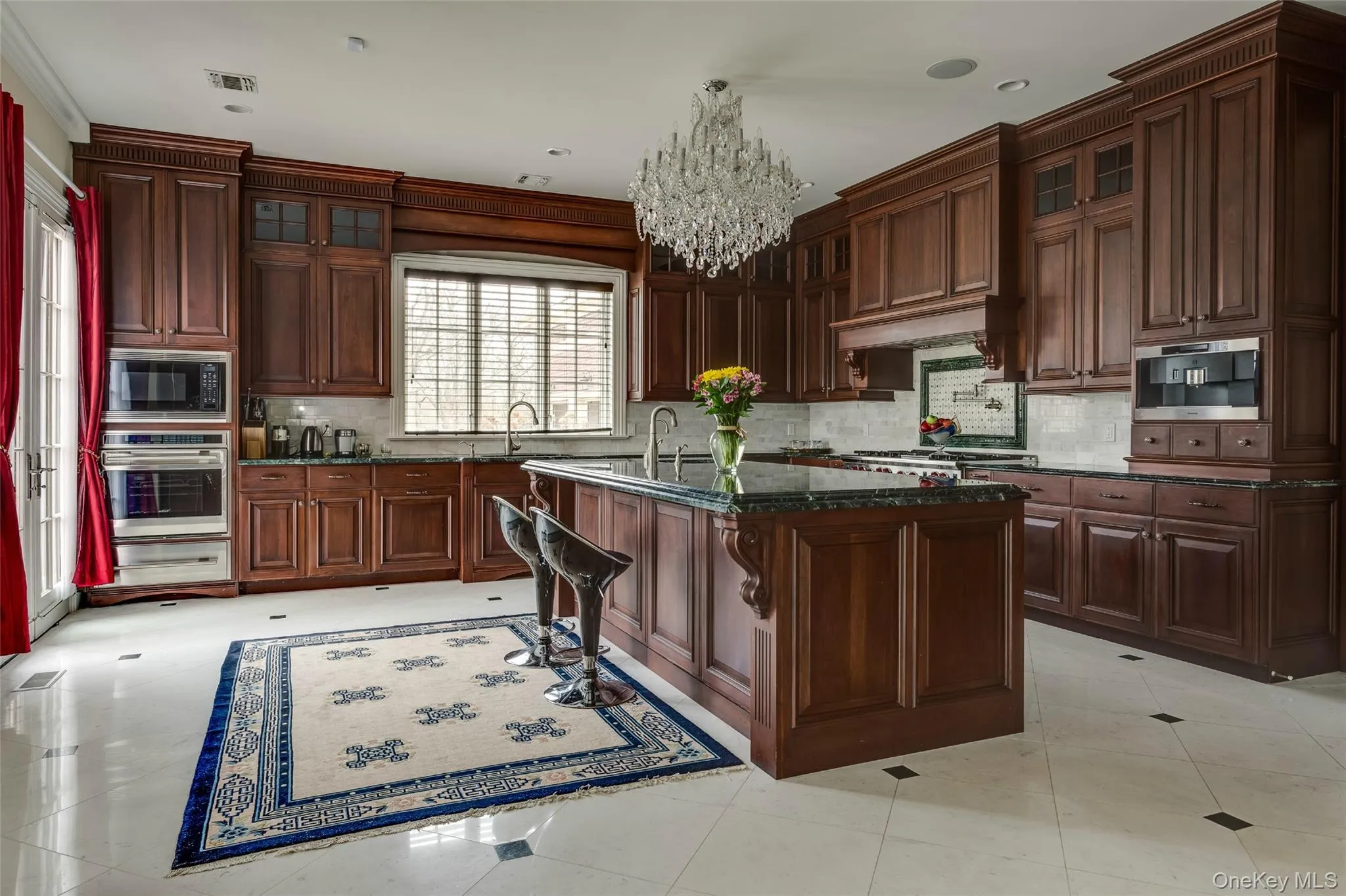 Kitchen with glass insert cabinets, a chandelier, dark stone countertops, stainless steel appliances, and crown molding Kitchen with glass insert cabinets, a chandelier, dark stone countertops, stainless steel appliances, and crown molding
