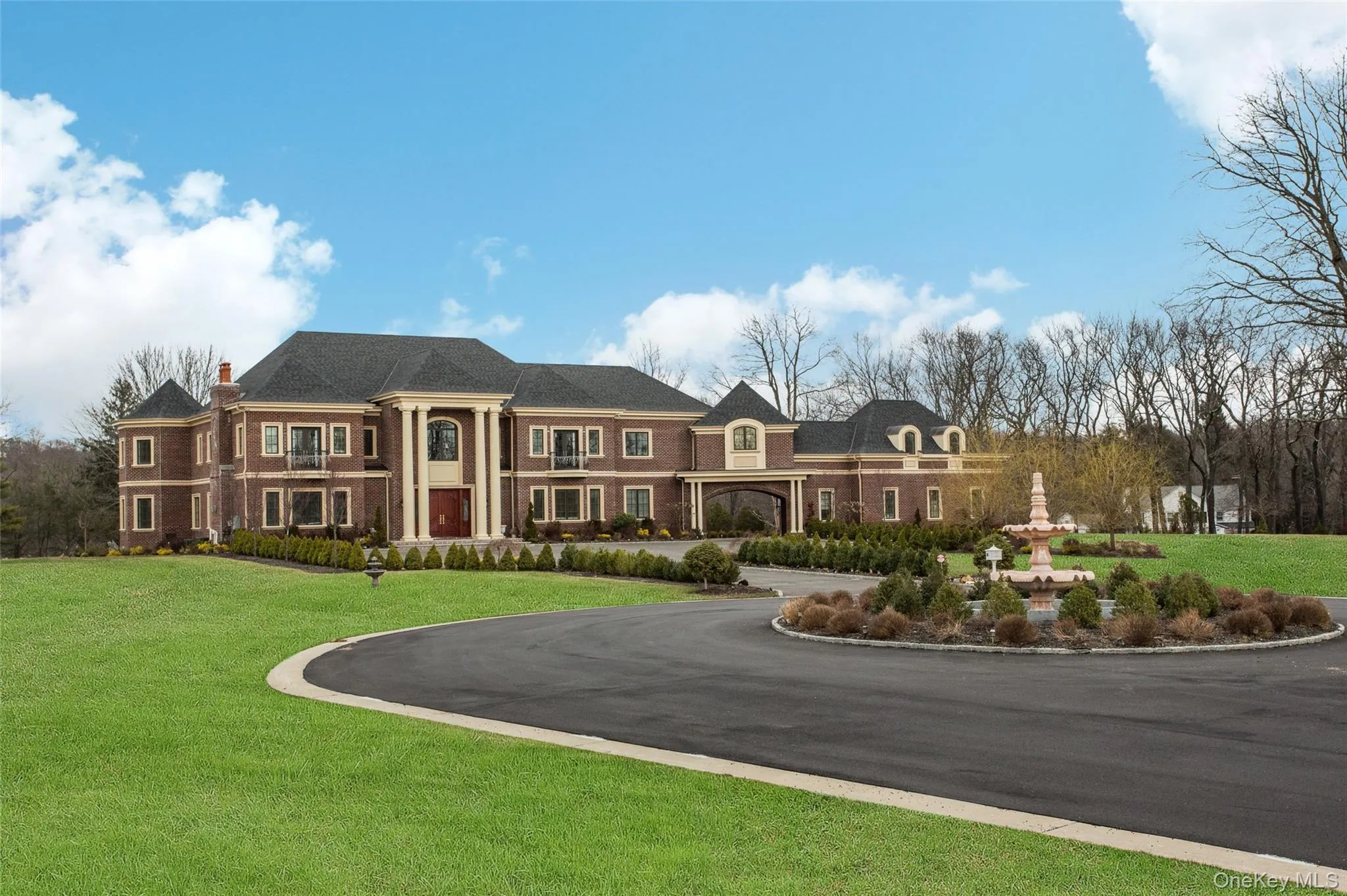 View of front of property featuring a front lawn, a chimney, curved driveway, and brick siding View of front of property featuring a front lawn, a chimney, curved driveway, and brick siding