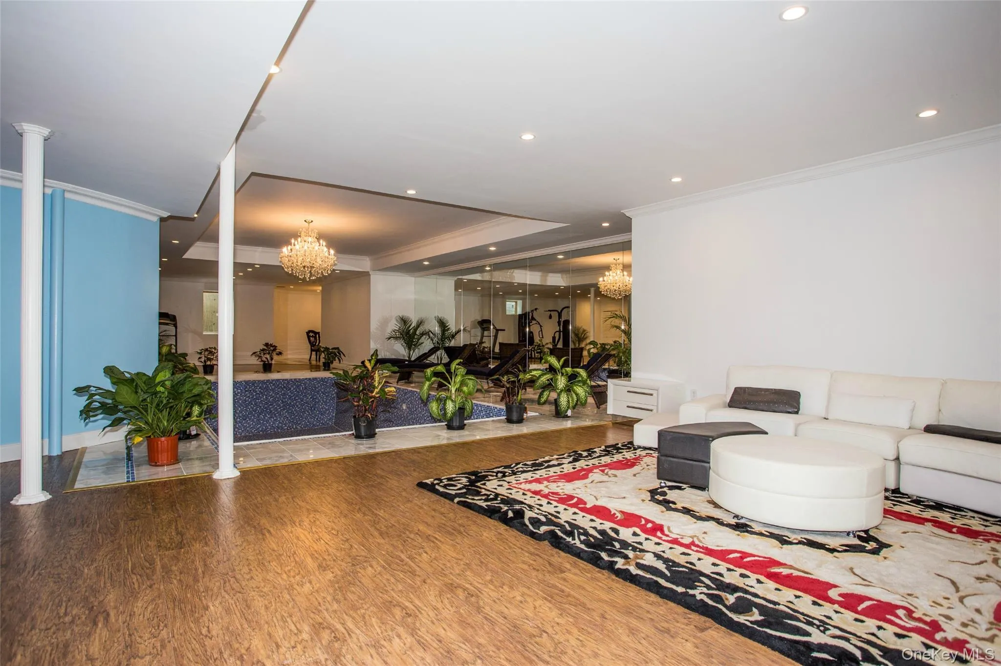 Living room featuring a raised ceiling, a chandelier, ornamental molding, wood finished floors, and recessed lighting Living room featuring a raised ceiling, a chandelier, ornamental molding, wood finished floors, and recessed lighting