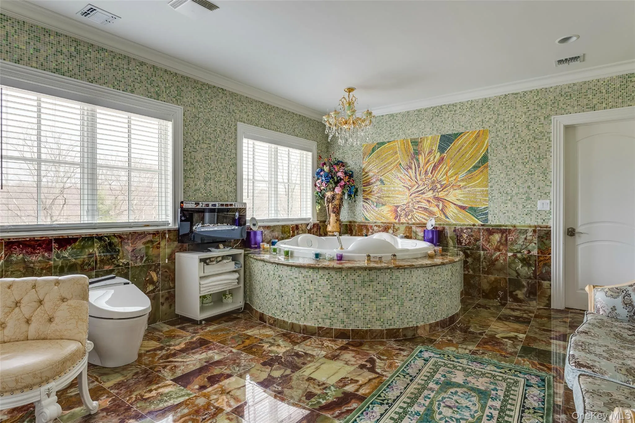 Full bathroom featuring tile walls, wainscoting, a bath, wallpapered walls, and a chandelier Full bathroom featuring tile walls, wainscoting, a bath, wallpapered walls, and a chandelier