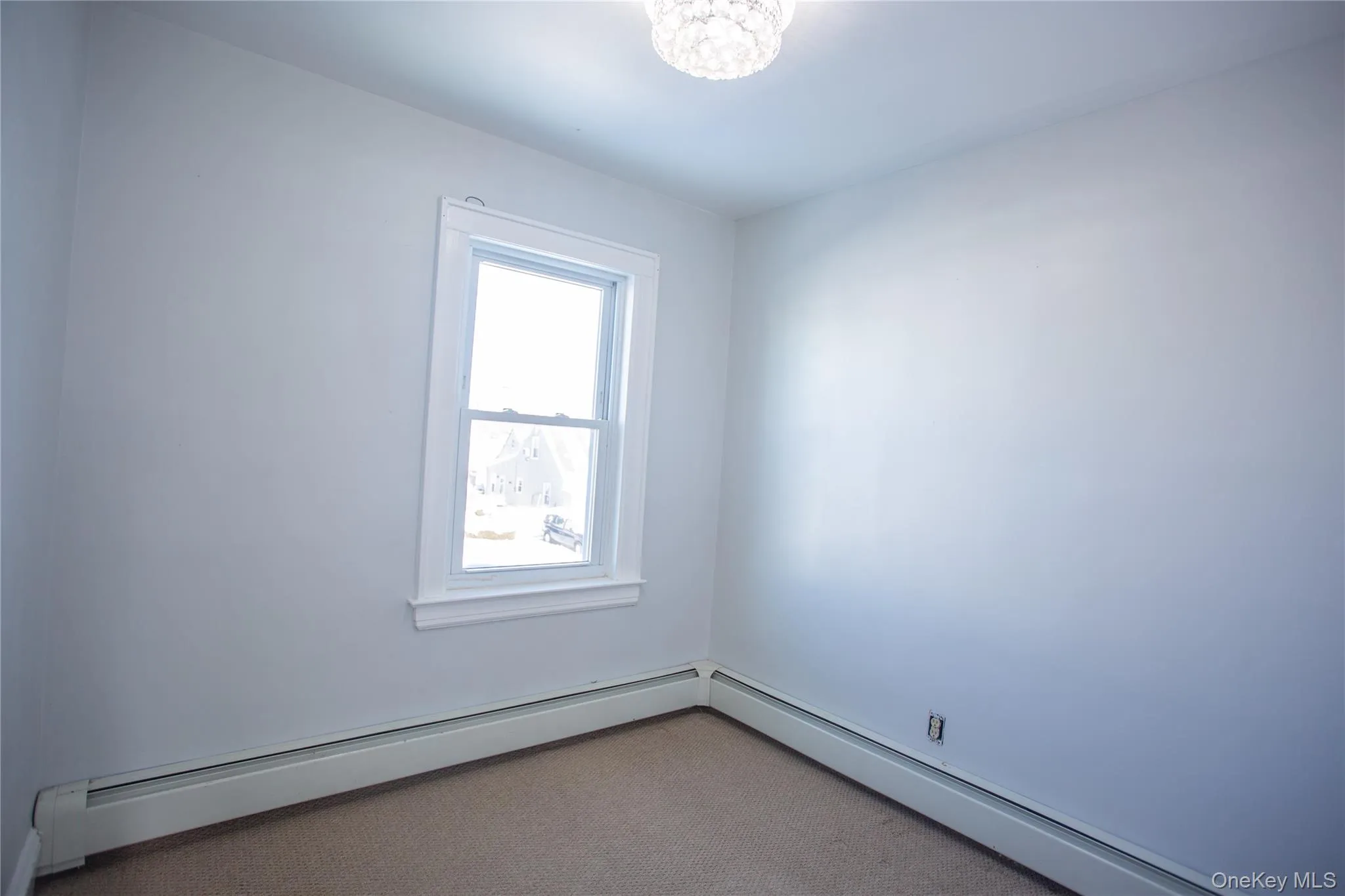 Spare room featuring baseboard heating, carpet flooring, and a chandelier Spare room featuring baseboard heating, carpet flooring, and a chandelier