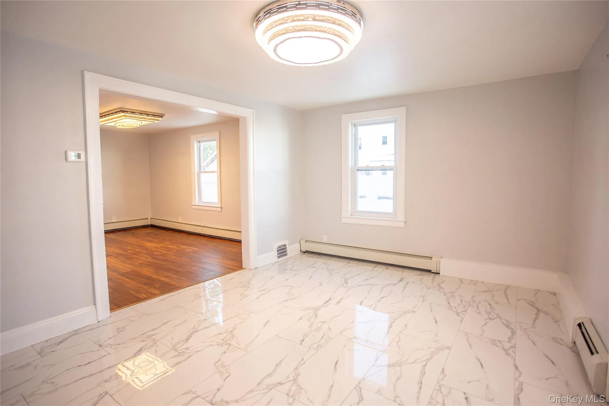 Empty room with marble look tiles, a baseboard heating unit, and a baseboard radiator Empty room with marble look tiles, a baseboard heating unit, and a baseboard radiator
