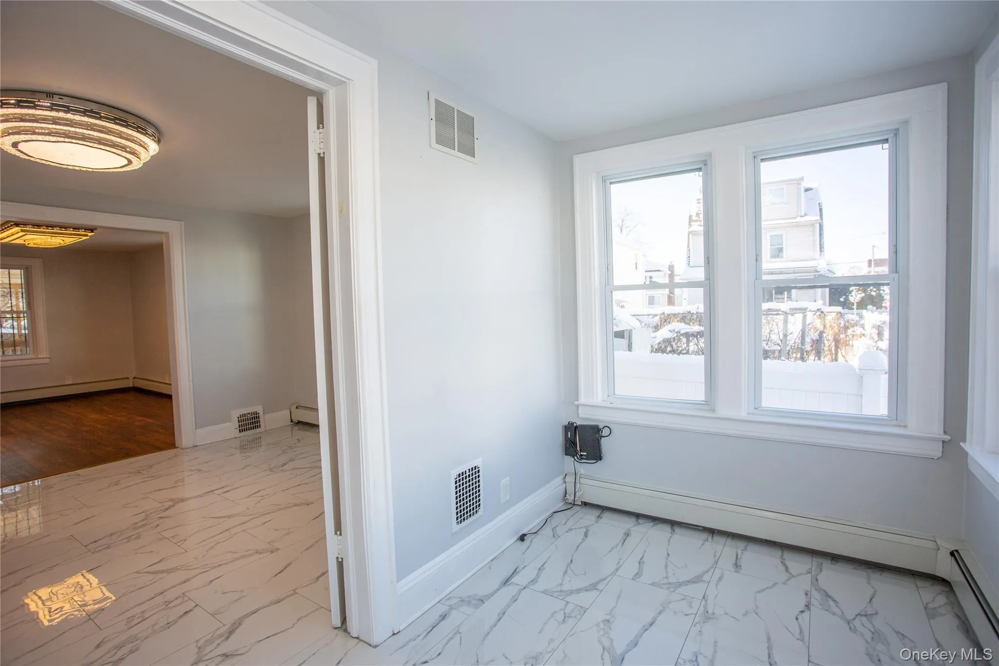 Unfurnished room featuring light marble finish floors, baseboard heating, plenty of natural light, and a baseboard radiator Unfurnished room featuring light marble finish floors, baseboard heating, plenty of natural light, and a baseboard radiator