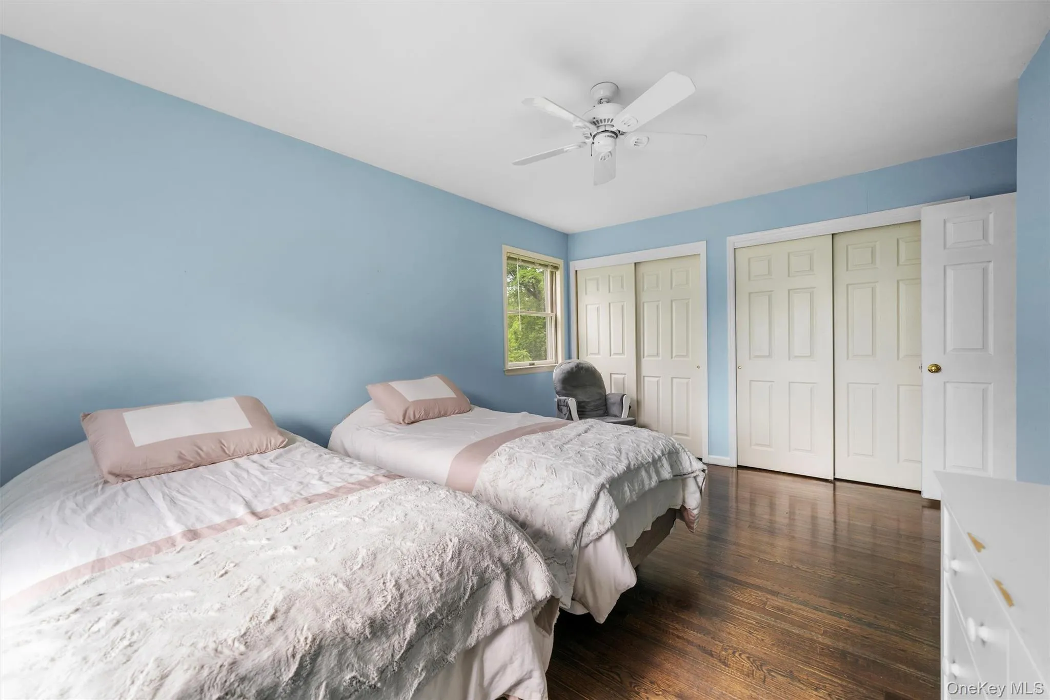 Bedroom featuring multiple closets, dark wood-style flooring, and a ceiling fan Bedroom featuring multiple closets, dark wood-style flooring, and a ceiling fan
