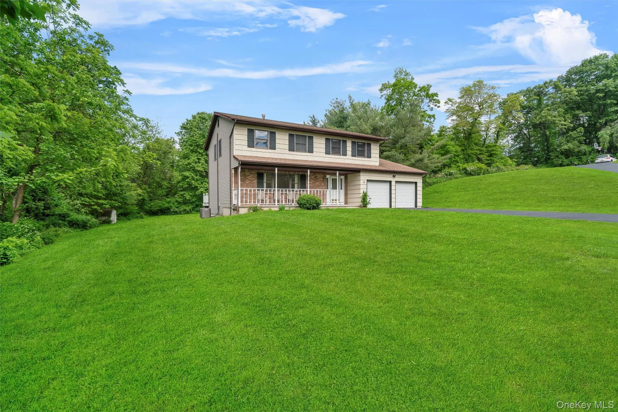 Traditional-style home with a front yard, a garage, a porch, and brick siding Traditional-style home with a front yard, a garage, a porch, and brick siding