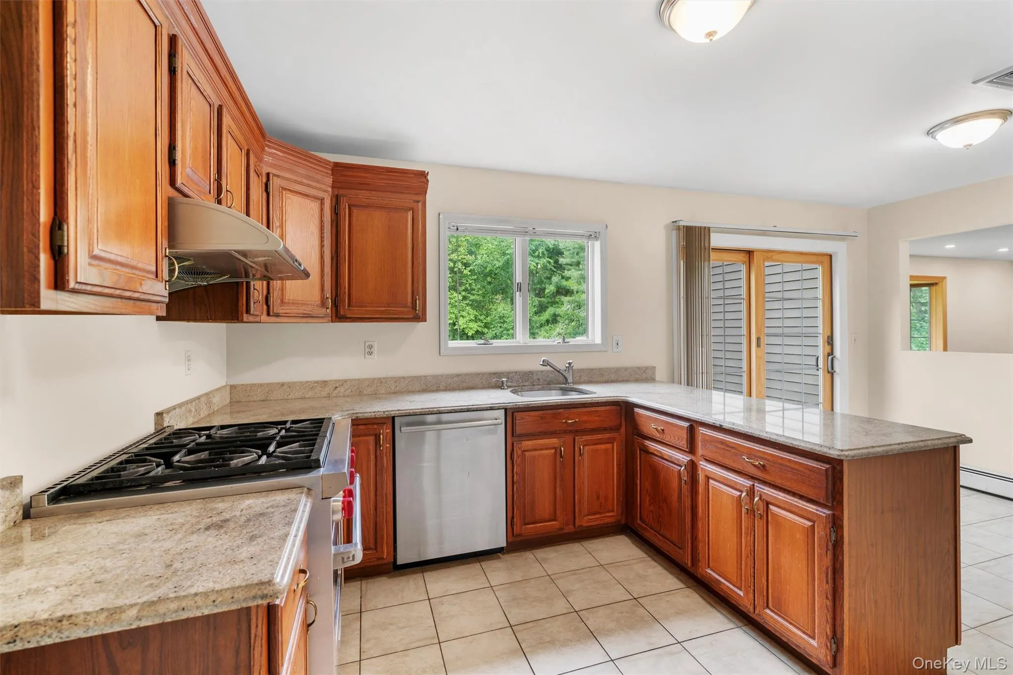 Kitchen with brown cabinetry, stainless steel appliances, a peninsula, and extractor fan Kitchen with brown cabinetry, stainless steel appliances, a peninsula, and extractor fan