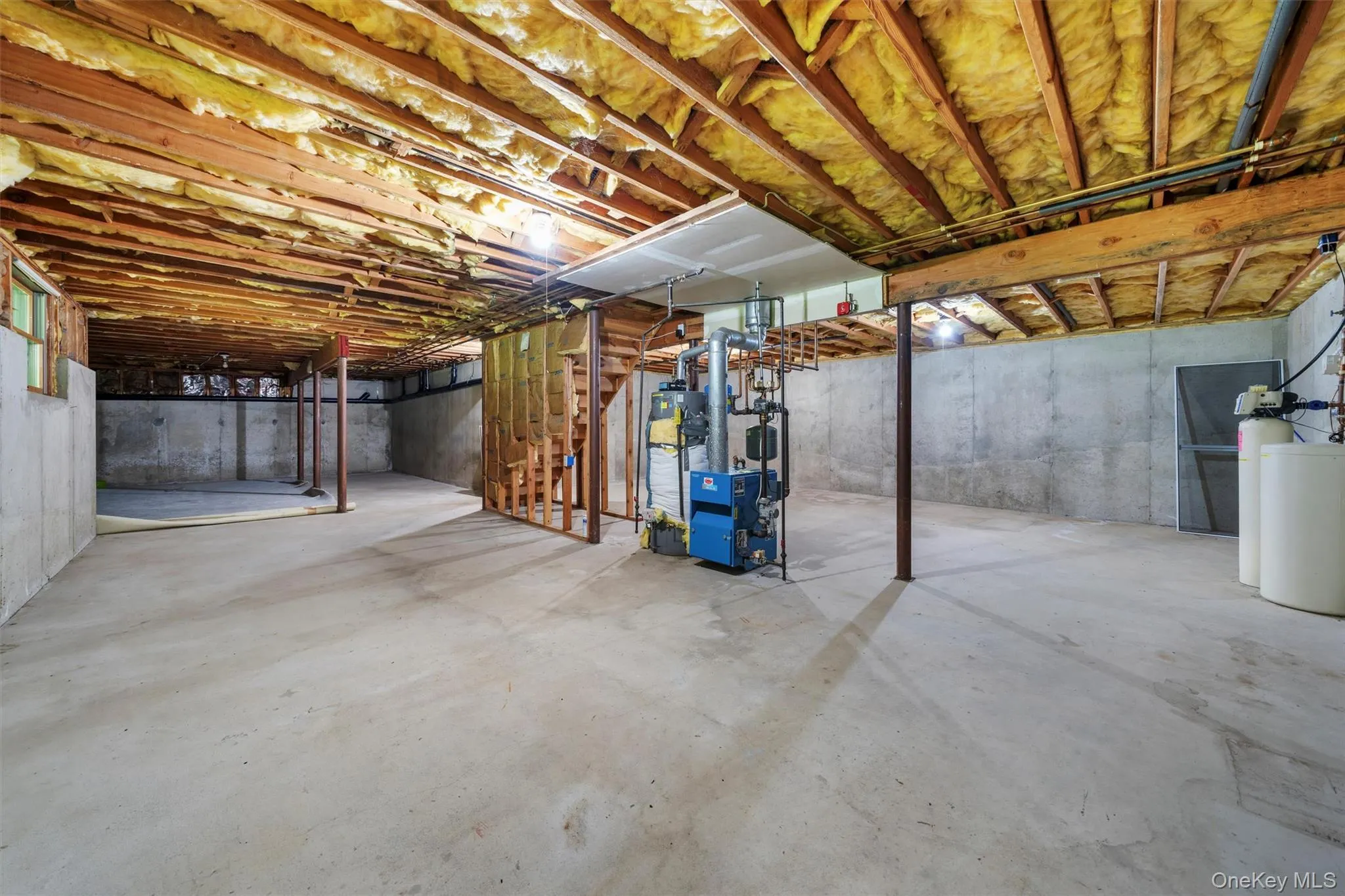 Unfinished basement with a water softener, water heater, and a heating unit Unfinished basement with a water softener, water heater, and a heating unit