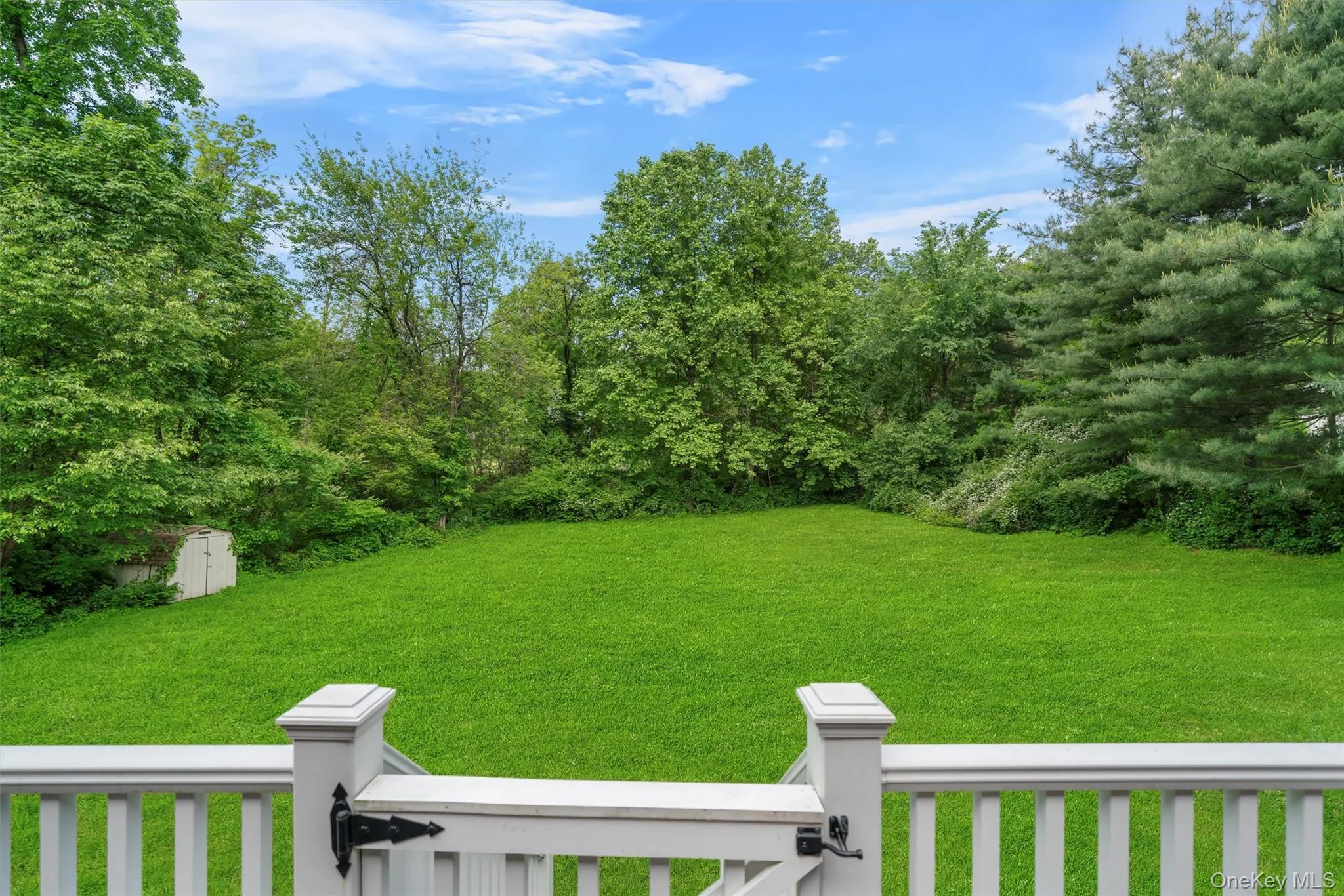 View of grassy yard featuring a storage unit and a balcony View of grassy yard featuring a storage unit and a balcony