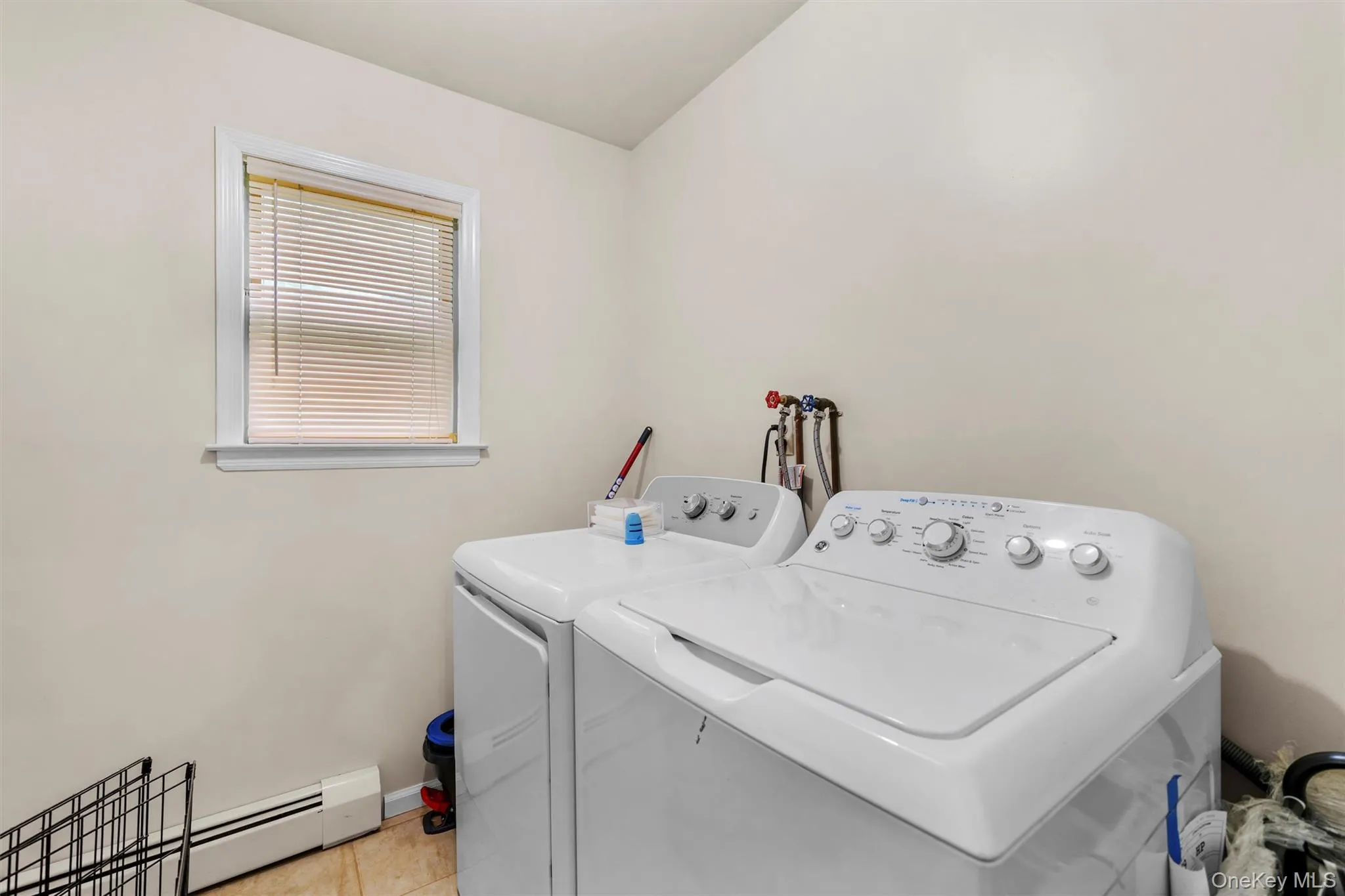 Laundry room with a baseboard heating unit, washing machine and dryer, and vaulted ceiling Laundry room with a baseboard heating unit, washing machine and dryer, and vaulted ceiling
