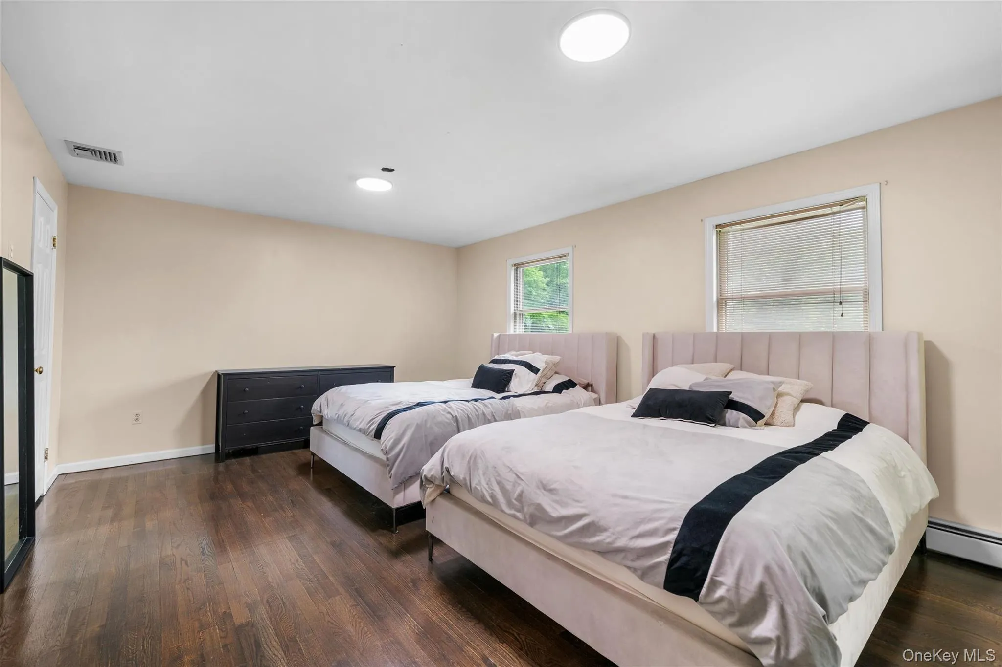 Bedroom with dark wood finished floors and a baseboard radiator Bedroom with dark wood finished floors and a baseboard radiator
