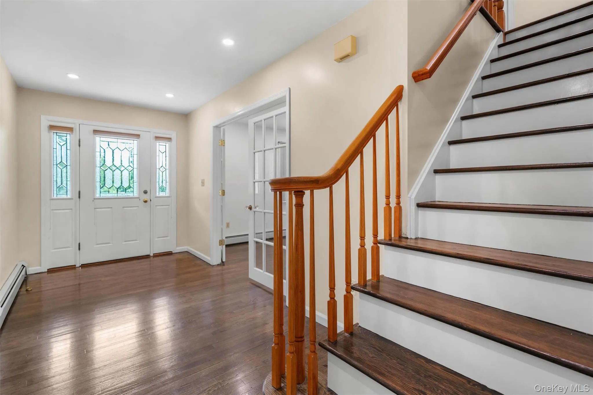 Foyer featuring dark wood-type flooring, stairway, recessed lighting, and a baseboard radiator Foyer featuring dark wood-type flooring, stairway, recessed lighting, and a baseboard radiator