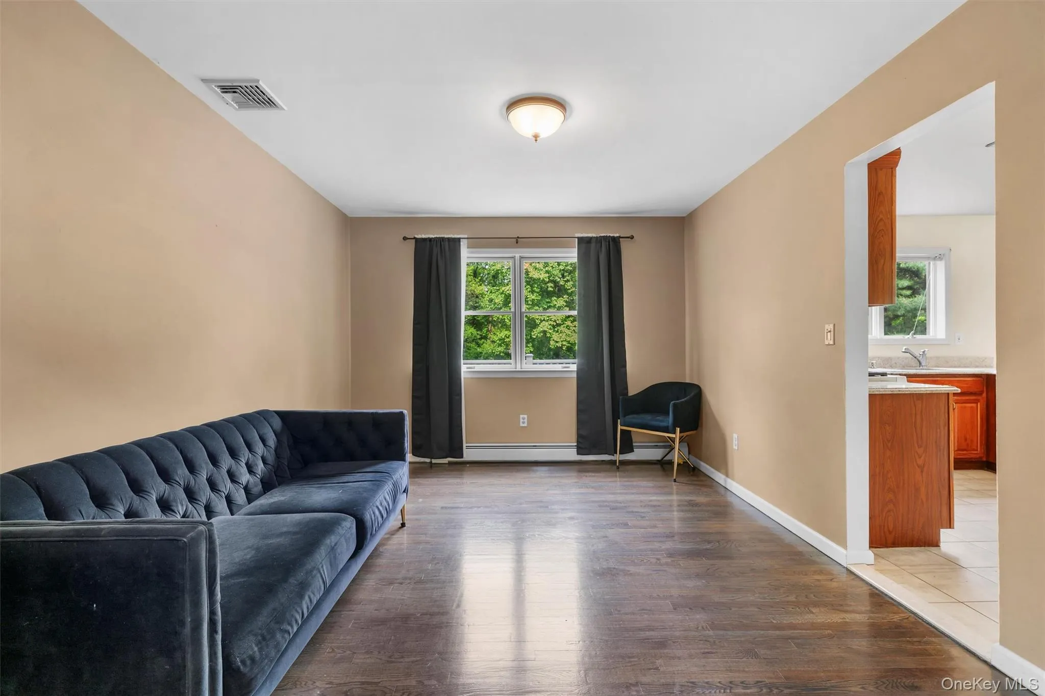 Sitting room featuring healthy amount of natural light, wood finished floors, and baseboard heating Sitting room featuring healthy amount of natural light, wood finished floors, and baseboard heating