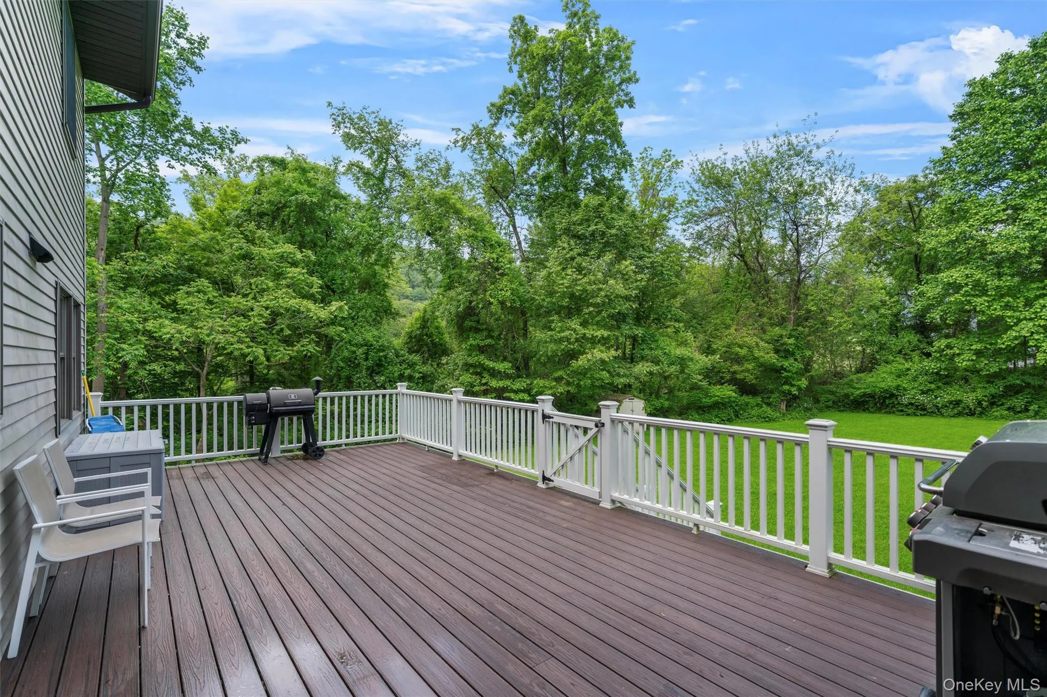 Deck with a lawn, a grill, and view of wooded area Deck with a lawn, a grill, and view of wooded area