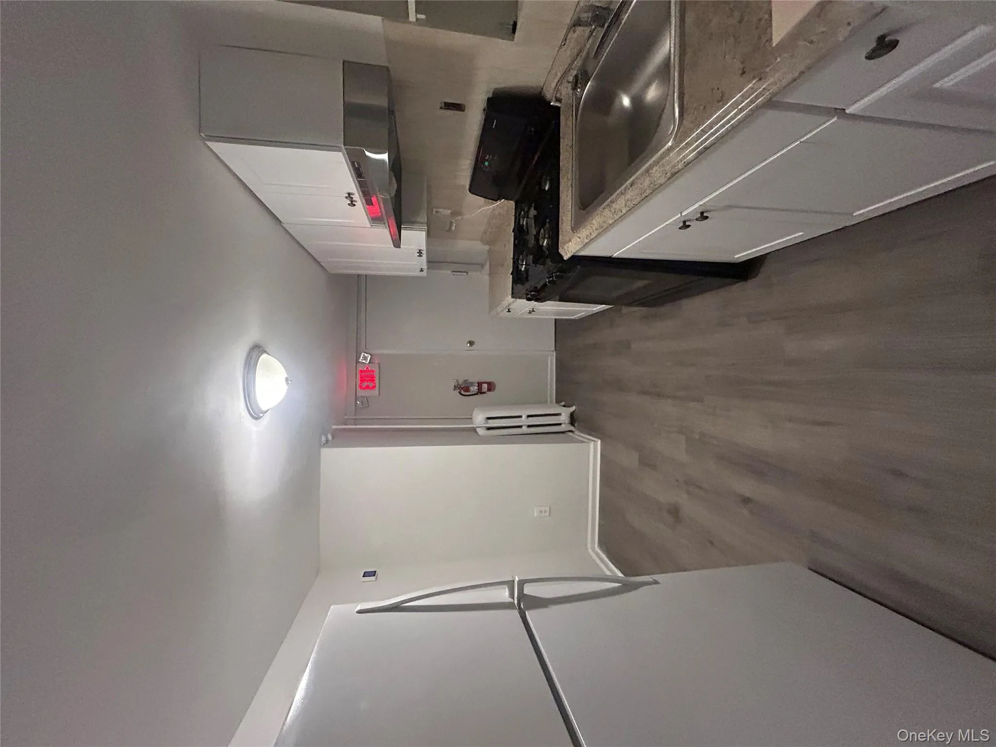 Kitchen featuring white cabinets, fridge, stove, dark wood-style floors, and light countertops Kitchen featuring white cabinets, fridge, stove, dark wood-style floors, and light countertops