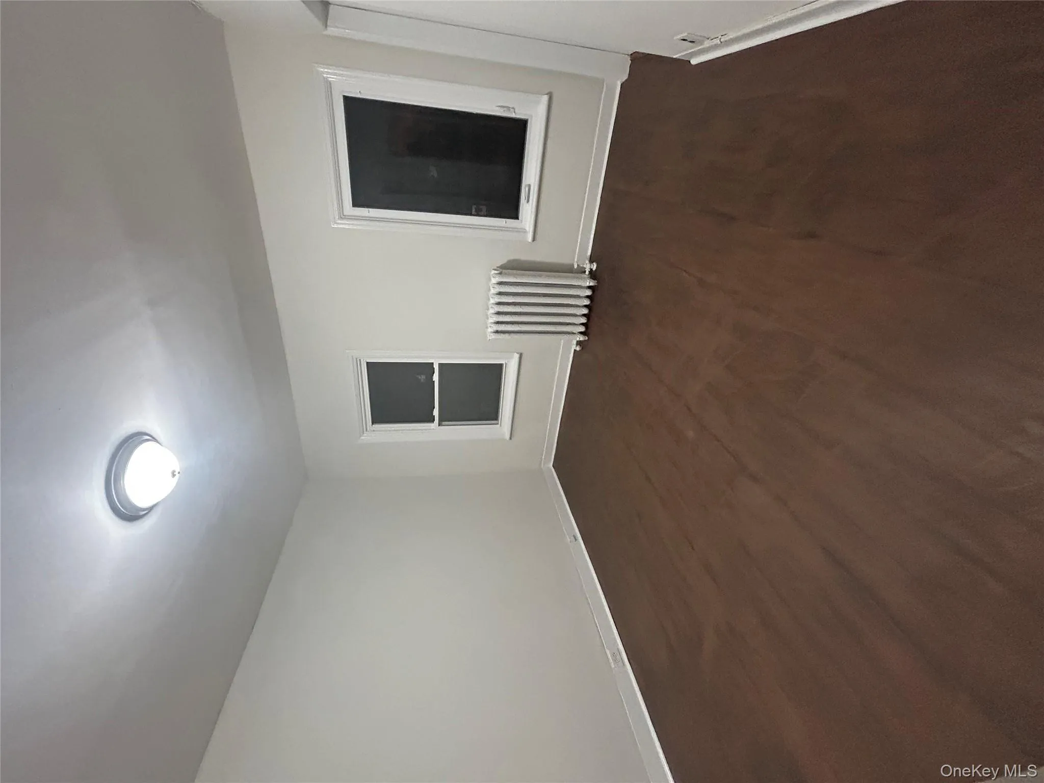 Unfurnished room featuring radiator and dark wood-style floors Unfurnished room featuring radiator and dark wood-style floors