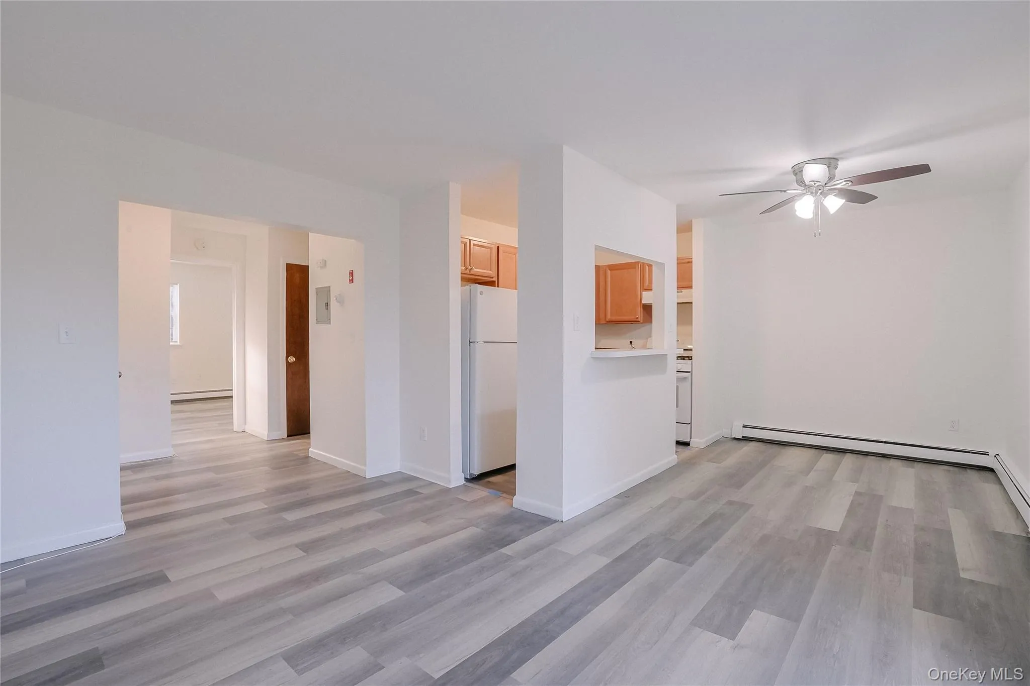 Unfurnished room with a ceiling fan, light wood-style floors, and a baseboard heating unit Unfurnished room with a ceiling fan, light wood-style floors, and a baseboard heating unit