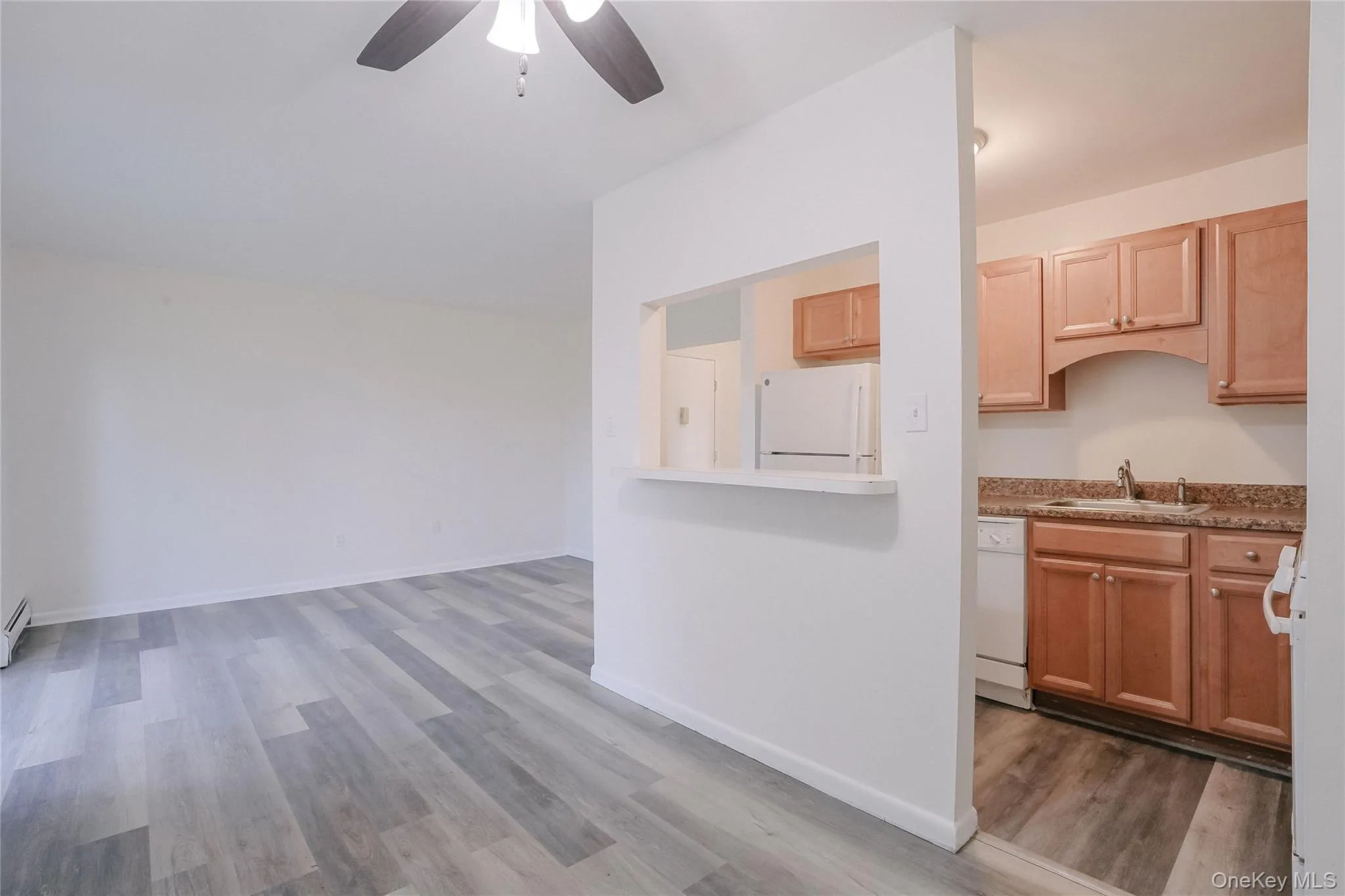 Kitchen featuring white appliances, light wood-style flooring, ceiling fan, and light brown cabinets Kitchen featuring white appliances, light wood-style flooring, ceiling fan, and light brown cabinets
