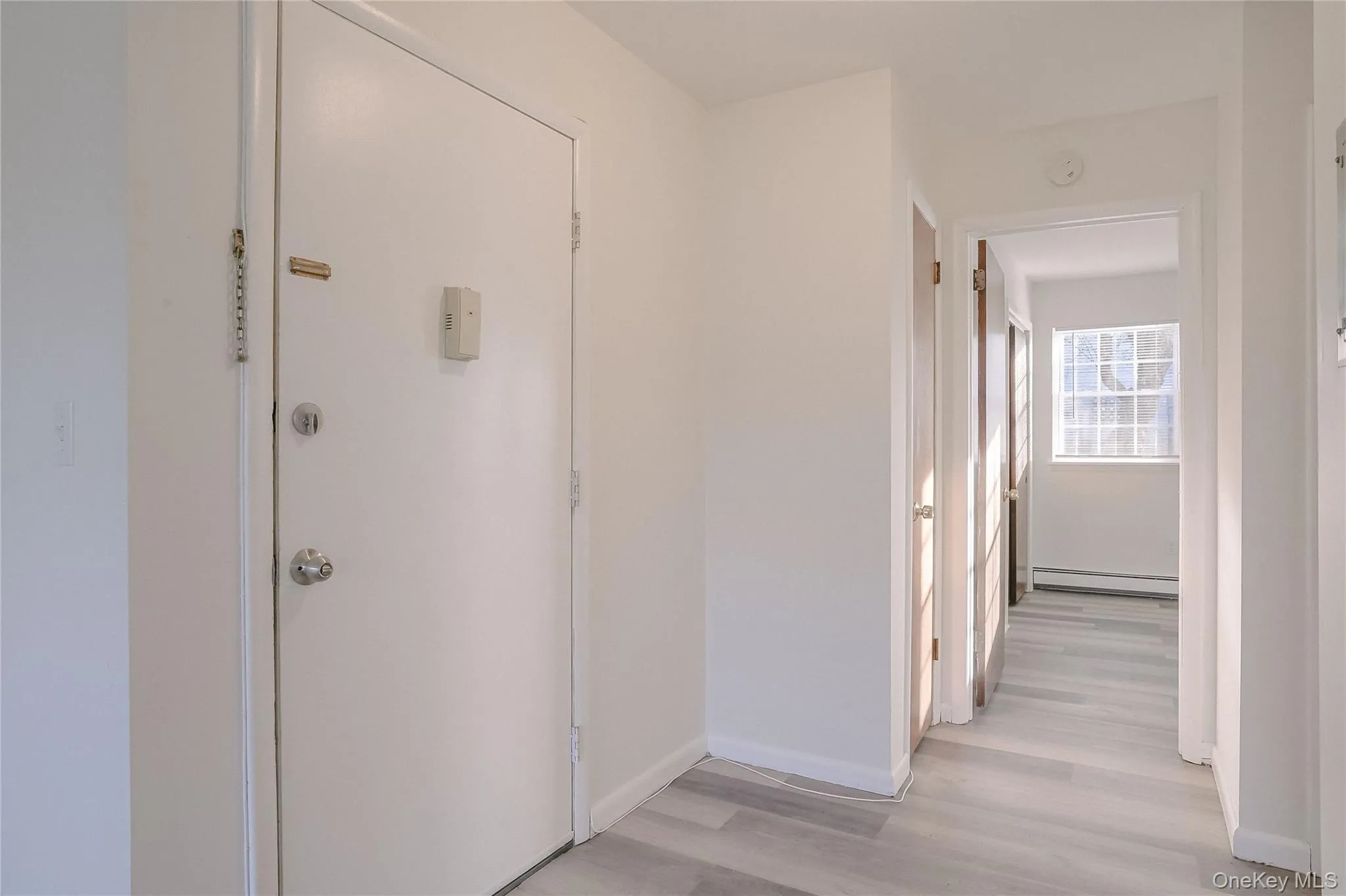 Corridor featuring light wood-style flooring and baseboard heating Corridor featuring light wood-style flooring and baseboard heating