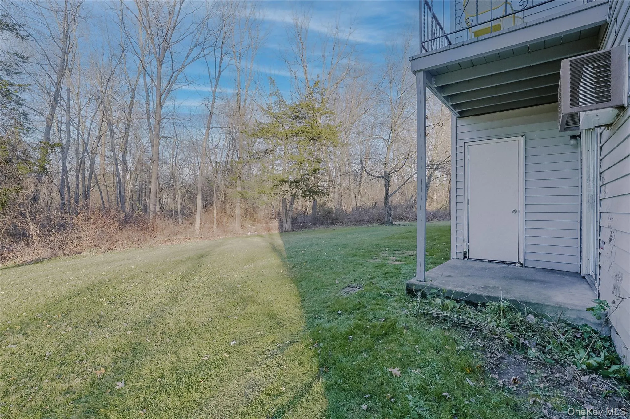 View of grassy yard featuring a balcony and a patio area View of grassy yard featuring a balcony and a patio area