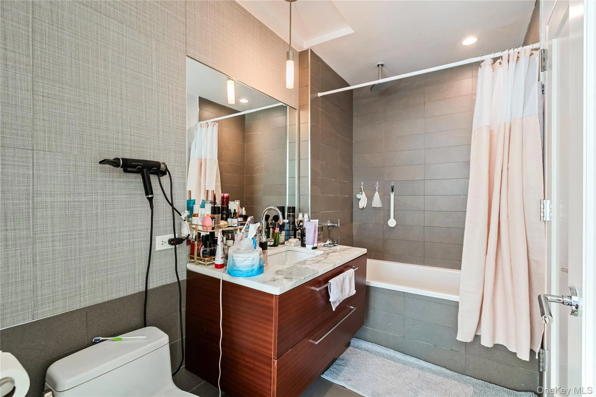 Full bath featuring vanity, a combined bath / shower with rainfall shower, tile walls, and recessed lighting Full bath featuring vanity, a combined bath / shower with rainfall shower, tile walls, and recessed lighting