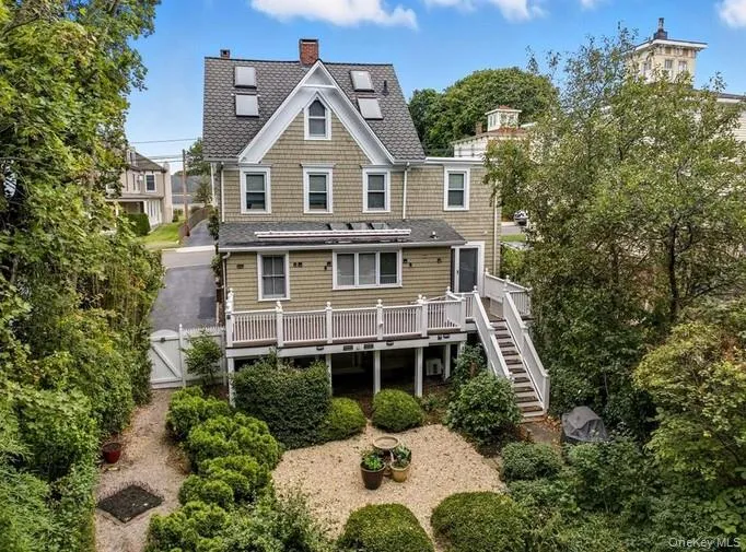 Rear view of property featuring a gate, a chimney, stairway, a deck, and a shingled roof Rear view of property featuring a gate, a chimney, stairway, a deck, and a shingled roof