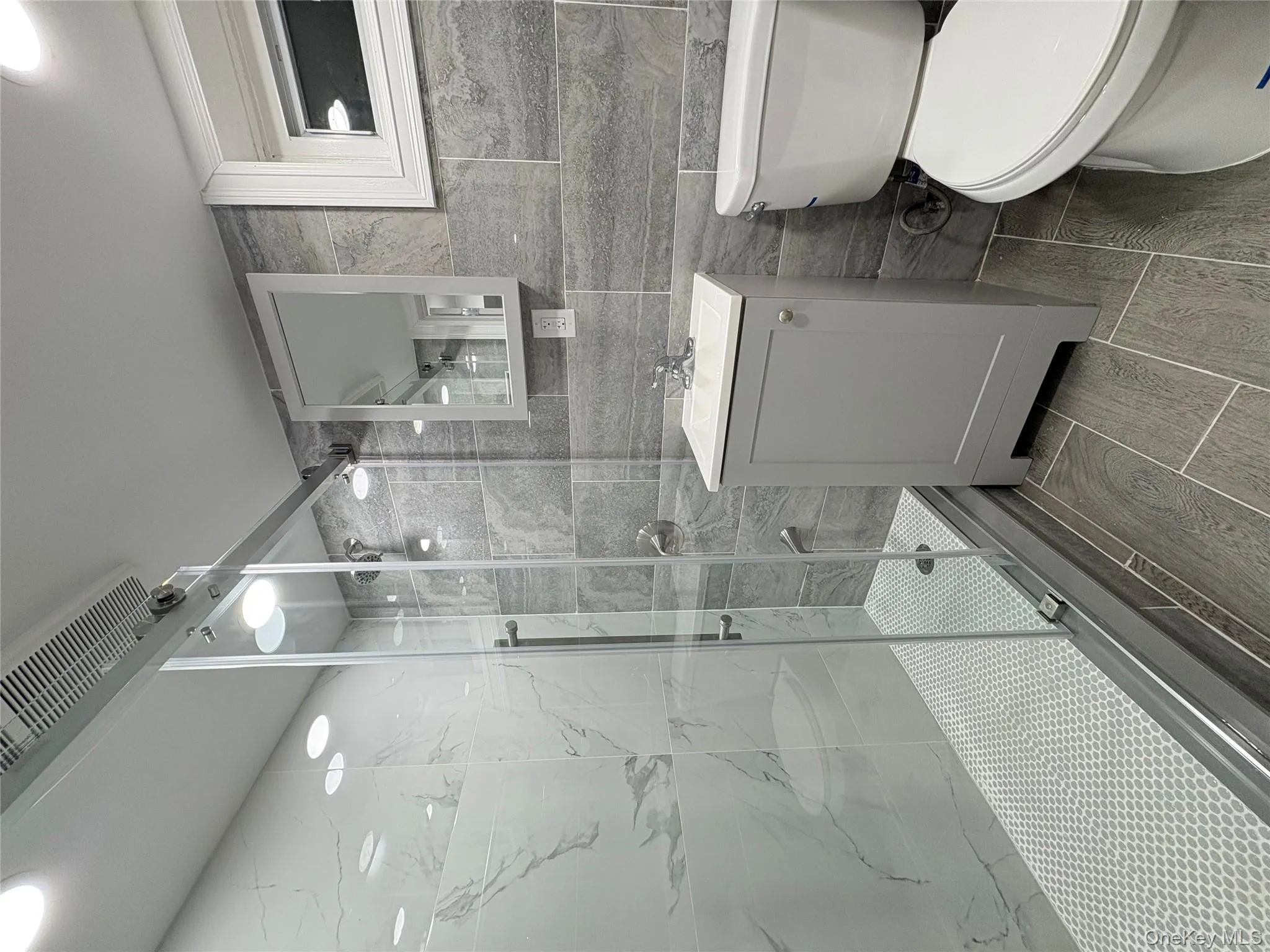 Bathroom featuring tile walls, a marble finish shower, vanity, and recessed lighting Bathroom featuring tile walls, a marble finish shower, vanity, and recessed lighting
