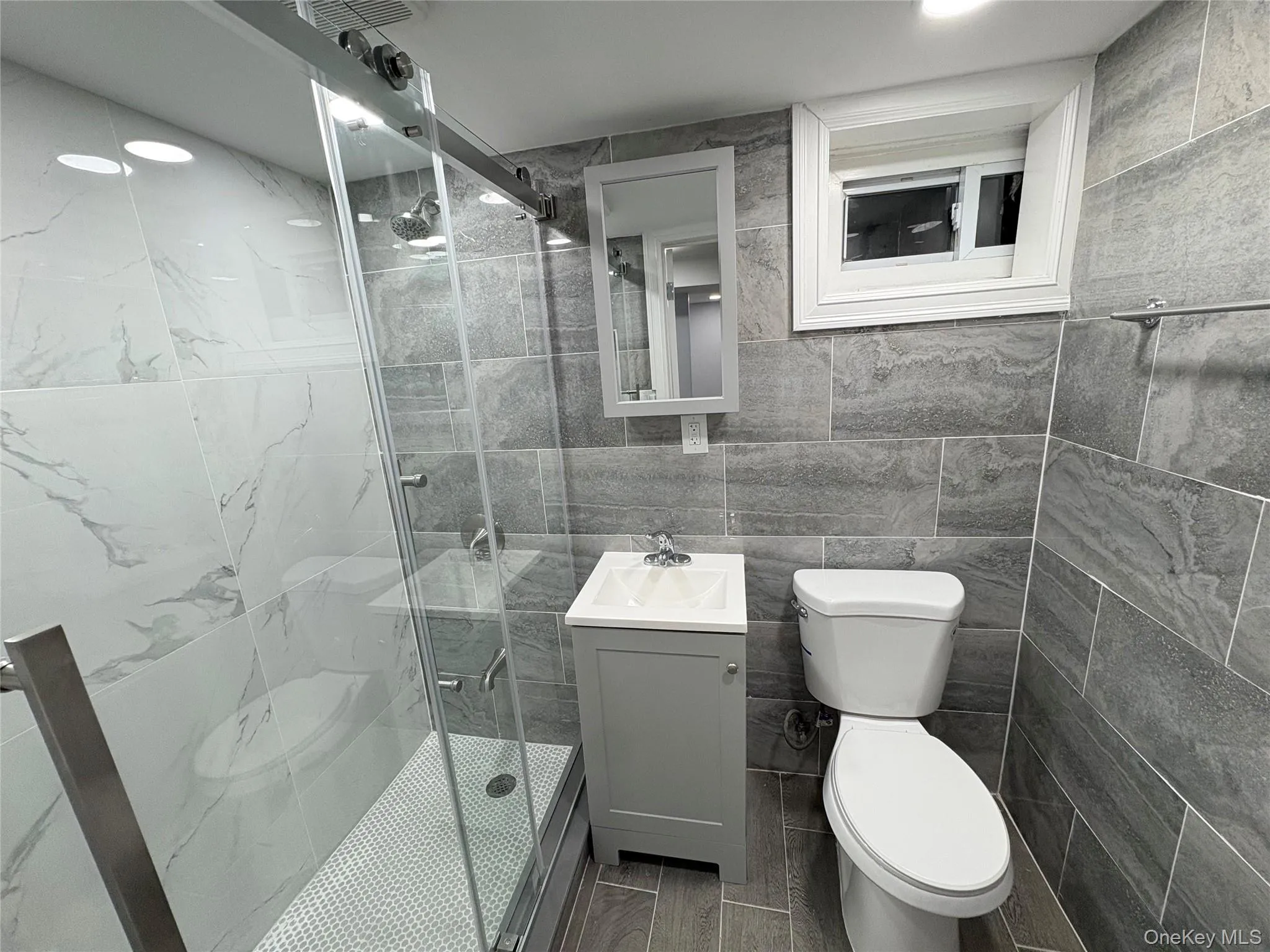 Full bathroom featuring tile walls, vanity, a marble finish shower, and recessed lighting Full bathroom featuring tile walls, vanity, a marble finish shower, and recessed lighting