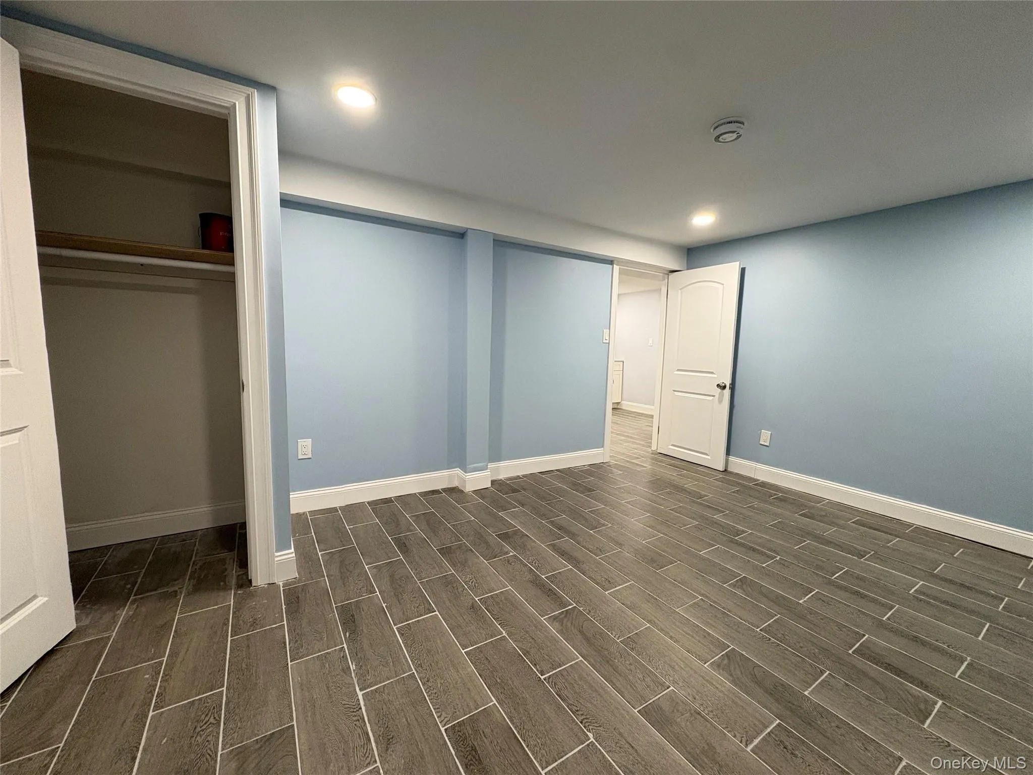 Unfurnished bedroom featuring wood tiled floors, a closet, and recessed lighting Unfurnished bedroom featuring wood tiled floors, a closet, and recessed lighting