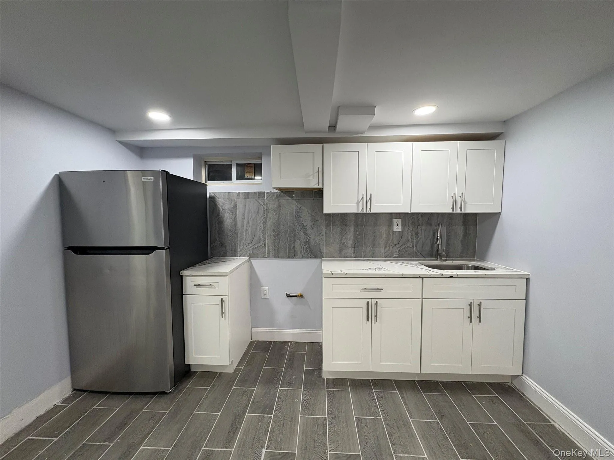 Kitchen with freestanding refrigerator, white cabinetry, wood finish floors, decorative backsplash, and recessed lighting Kitchen with freestanding refrigerator, white cabinetry, wood finish floors, decorative backsplash, and recessed lighting