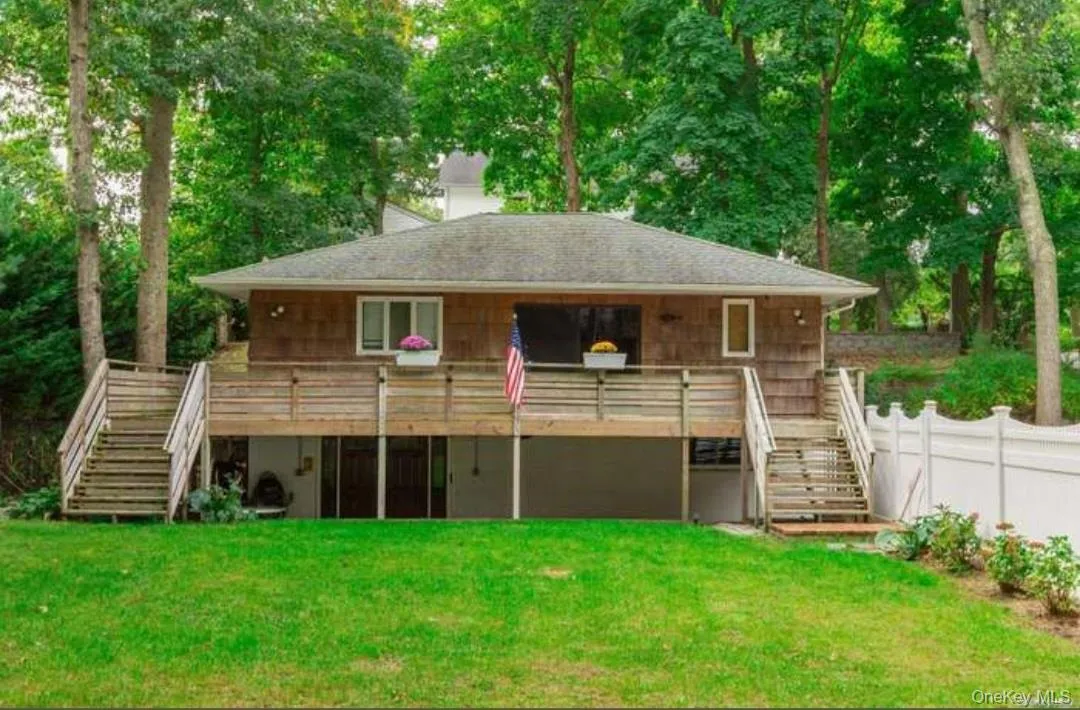Back of property with stairway, a wooden deck, and roof with shingles Back of property with stairway, a wooden deck, and roof with shingles