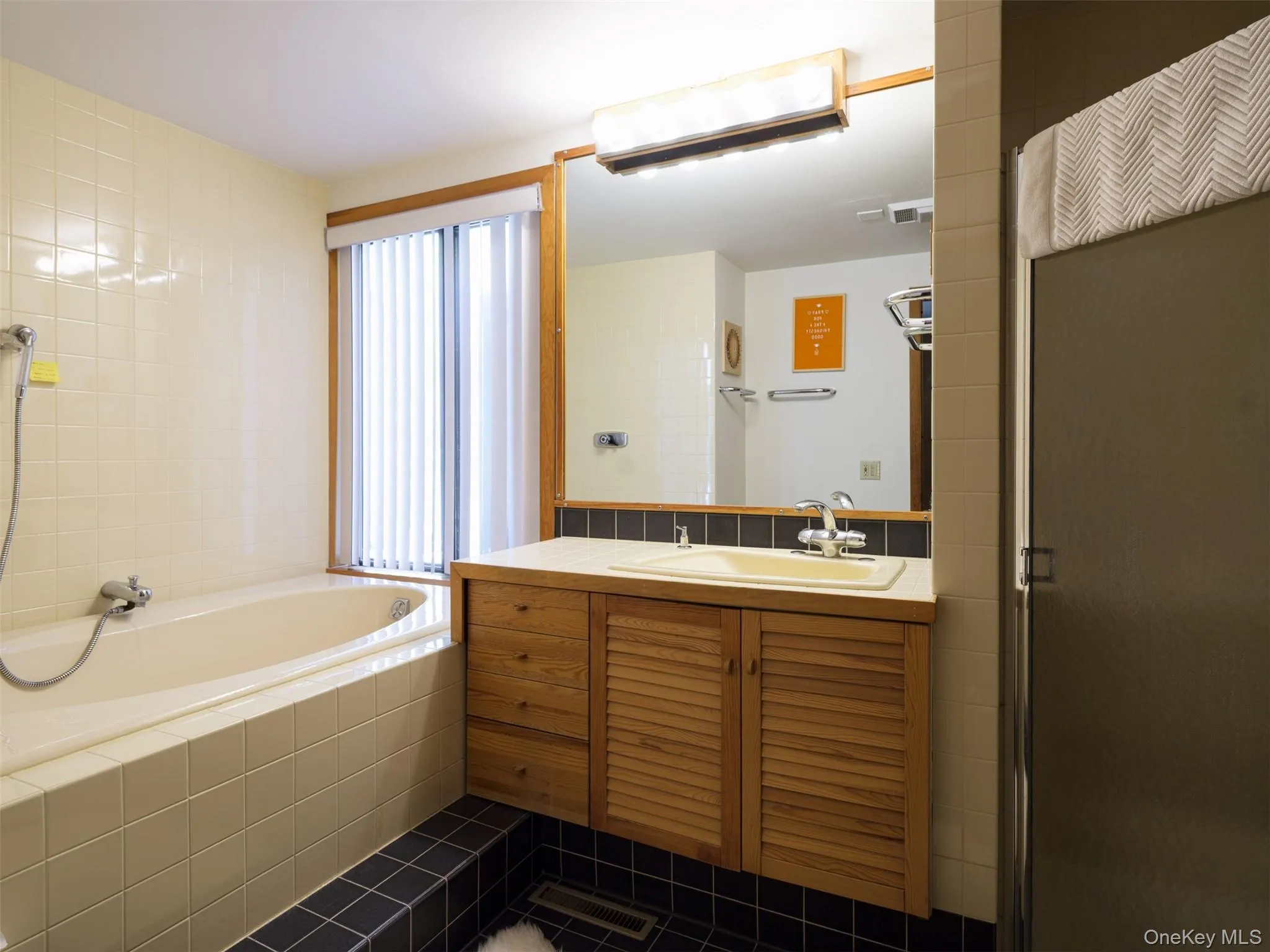 Bathroom featuring vanity, a shower, dark tile patterned floors, and a relaxing tiled tub Bathroom featuring vanity, a shower, dark tile patterned floors, and a relaxing tiled tub
