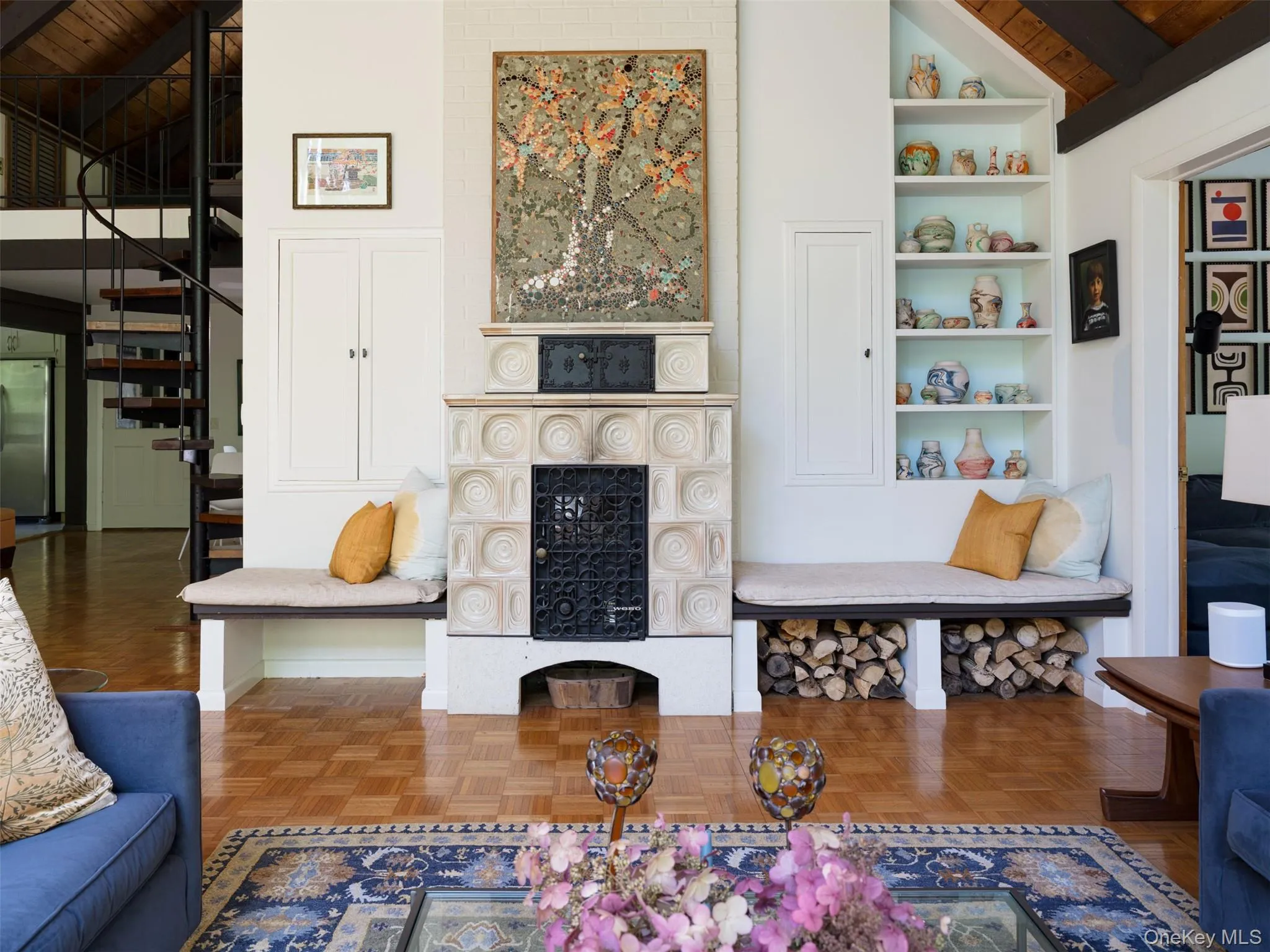 Living area with a wood ceiling with exposed beams, built in features, stairs, a large fireplace, and high vaulted ceiling Living area with a wood ceiling with exposed beams, built in features, stairs, a large fireplace, and high vaulted ceiling