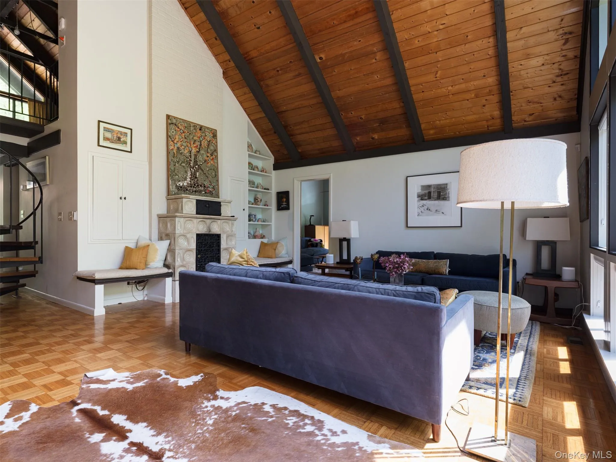 Living area featuring high vaulted ceiling, a wood ceiling with exposed beams, a stone fireplace, built in shelves, and stairway Living area featuring high vaulted ceiling, a wood ceiling with exposed beams, a stone fireplace, built in shelves, and stairway