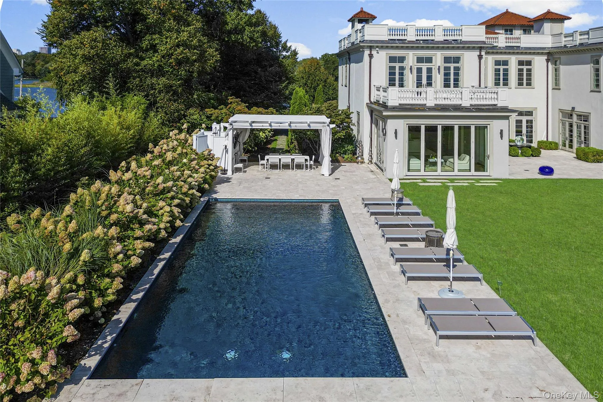 Back of property featuring a patio area, stucco siding, an outdoor pool, a yard, and a balcony Back of property featuring a patio area, stucco siding, an outdoor pool, a yard, and a balcony