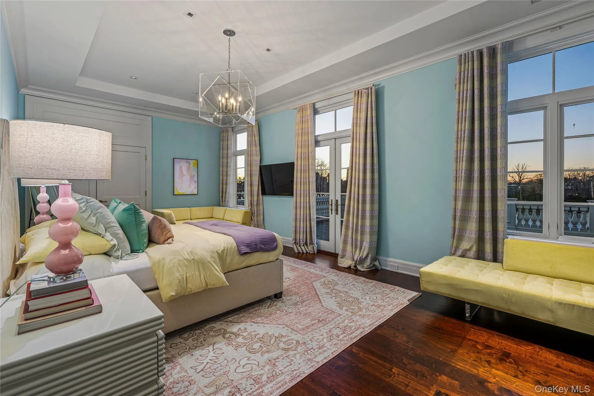 Bedroom featuring dark wood-style floors, a raised ceiling, and a chandelier Bedroom featuring dark wood-style floors, a raised ceiling, and a chandelier